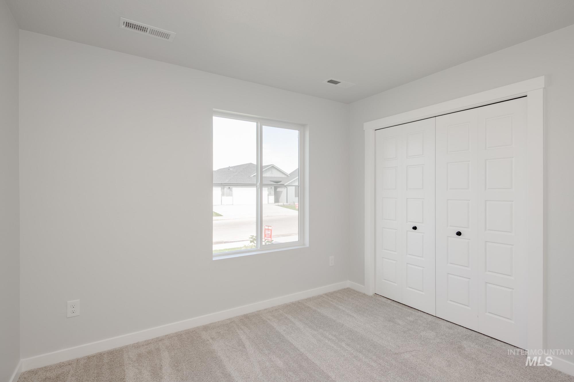 Unfurnished bedroom with light colored carpet and a closet