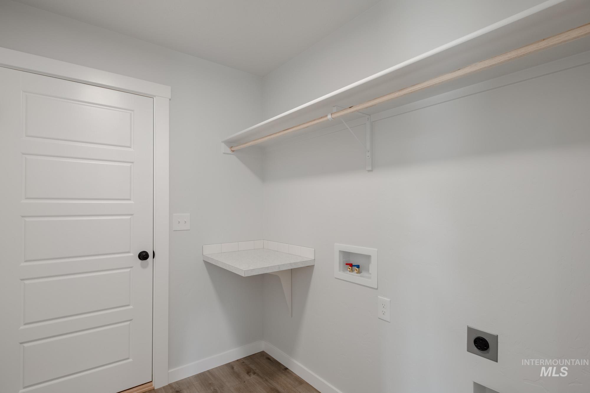 Washroom with hookup for a washing machine, light wood finished floors, and hookup for an electric dryer