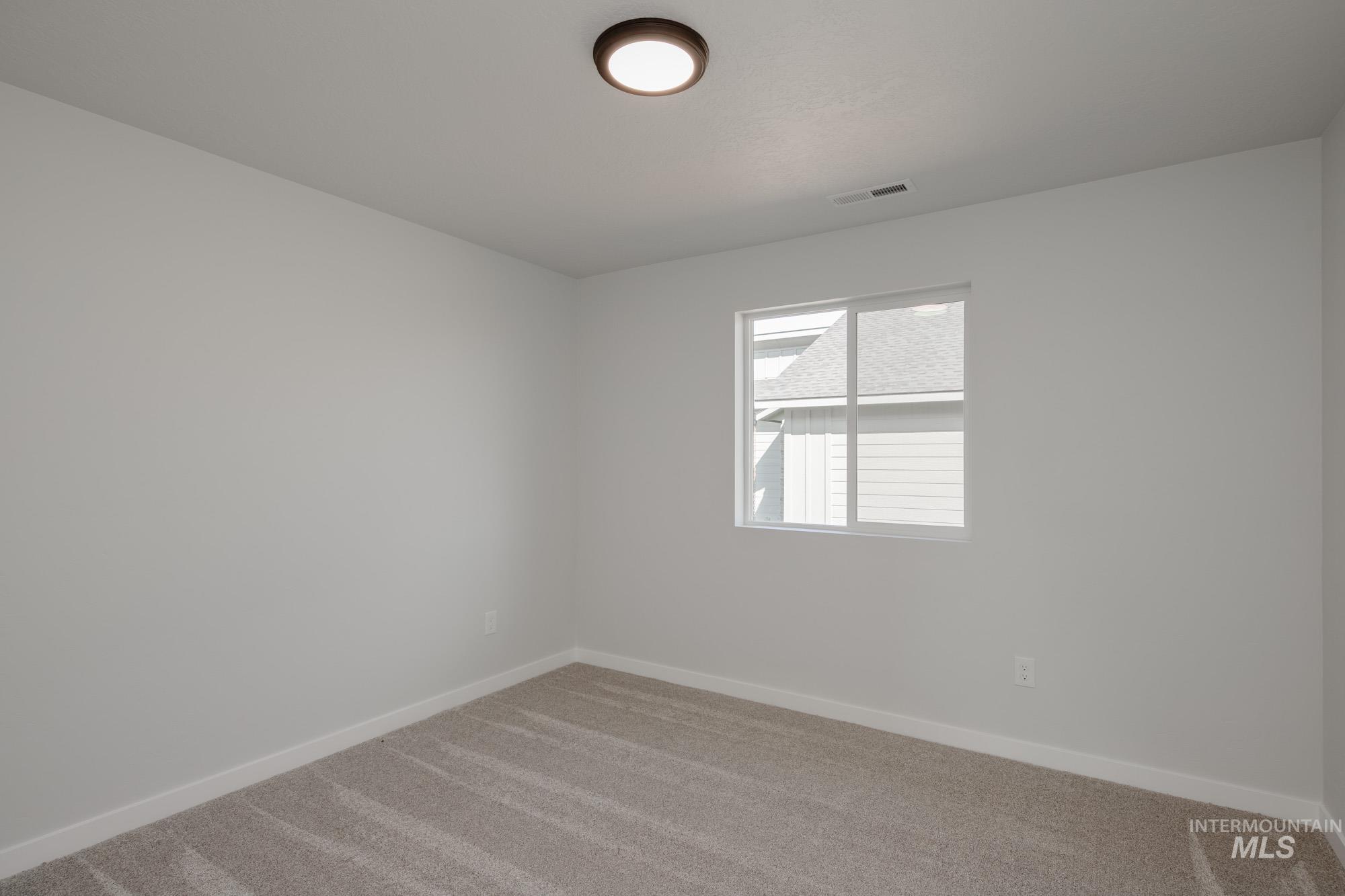 Carpeted spare room with baseboards