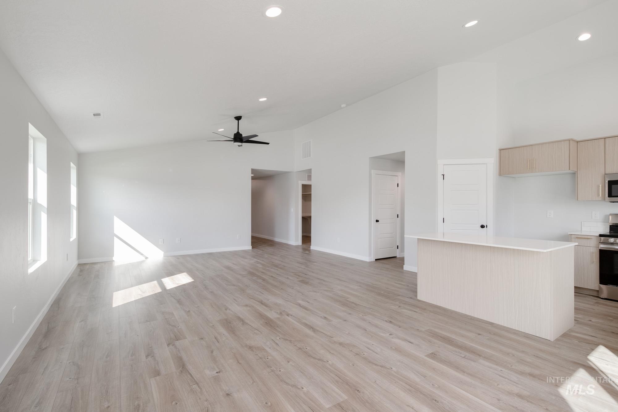 Unfurnished living room with light wood-type flooring, high vaulted ceiling, recessed lighting, and ceiling fan