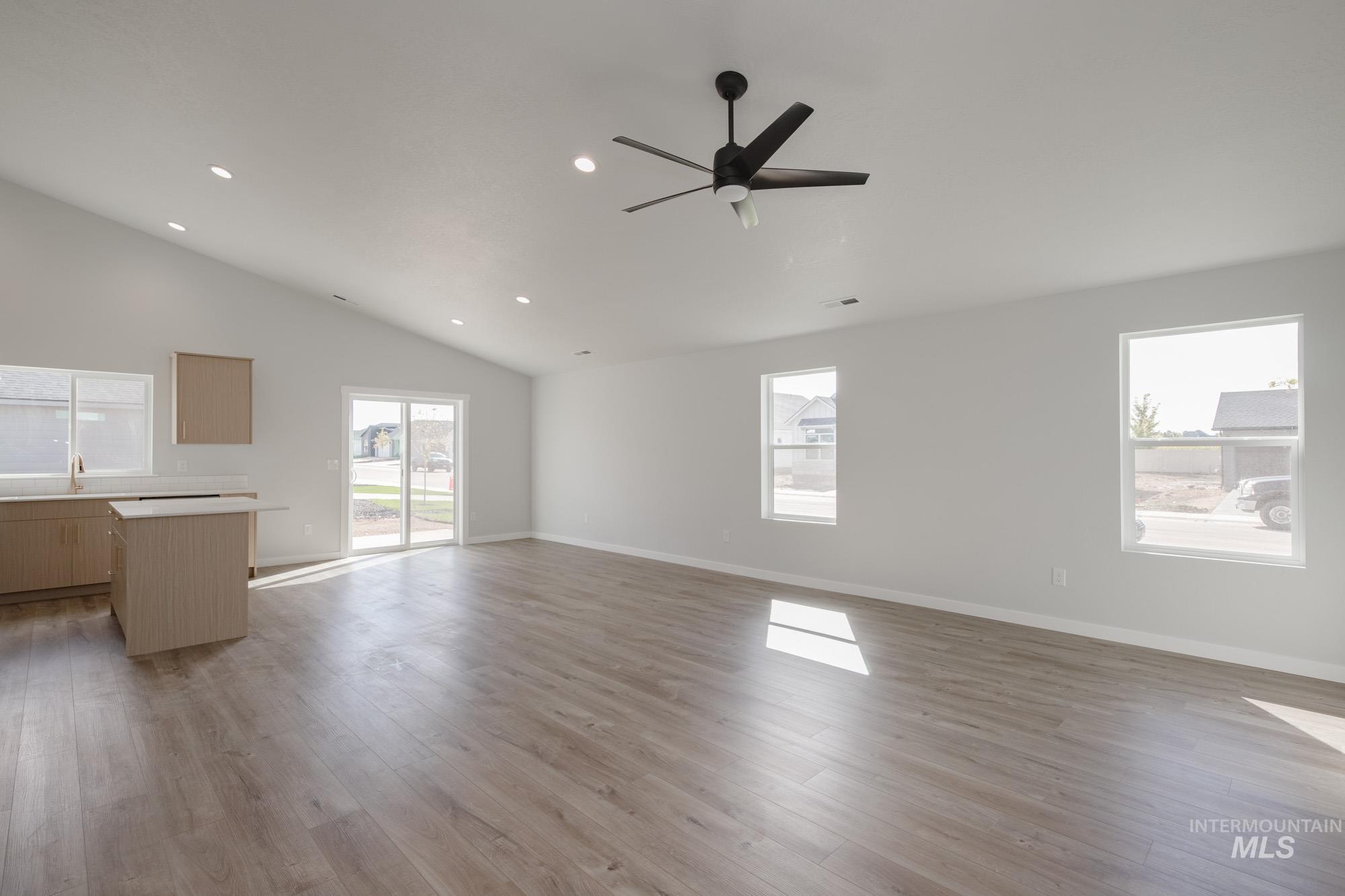 Unfurnished living room featuring light wood finished floors, recessed lighting, ceiling fan, and high vaulted ceiling