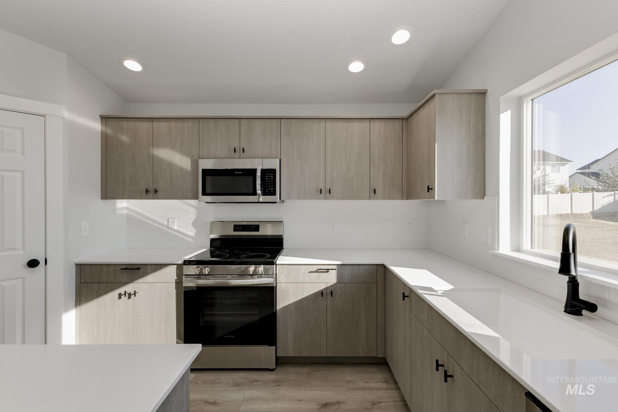 Kitchen featuring stainless steel appliances, light wood-type flooring, recessed lighting, light brown cabinetry, and decorative backsplash
