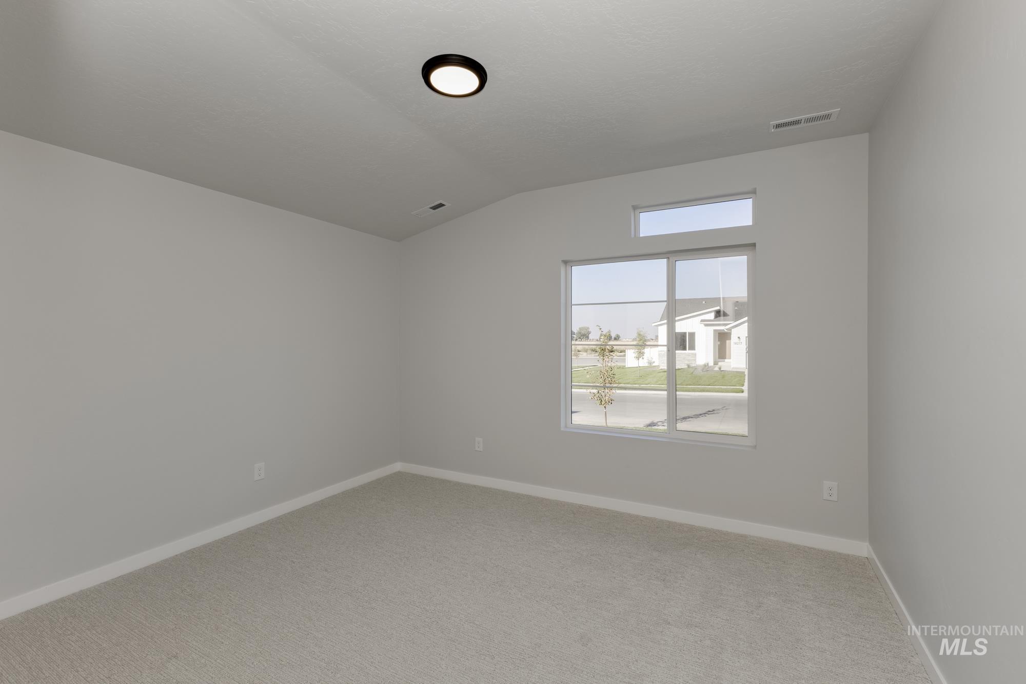 Empty room featuring vaulted ceiling and light carpet