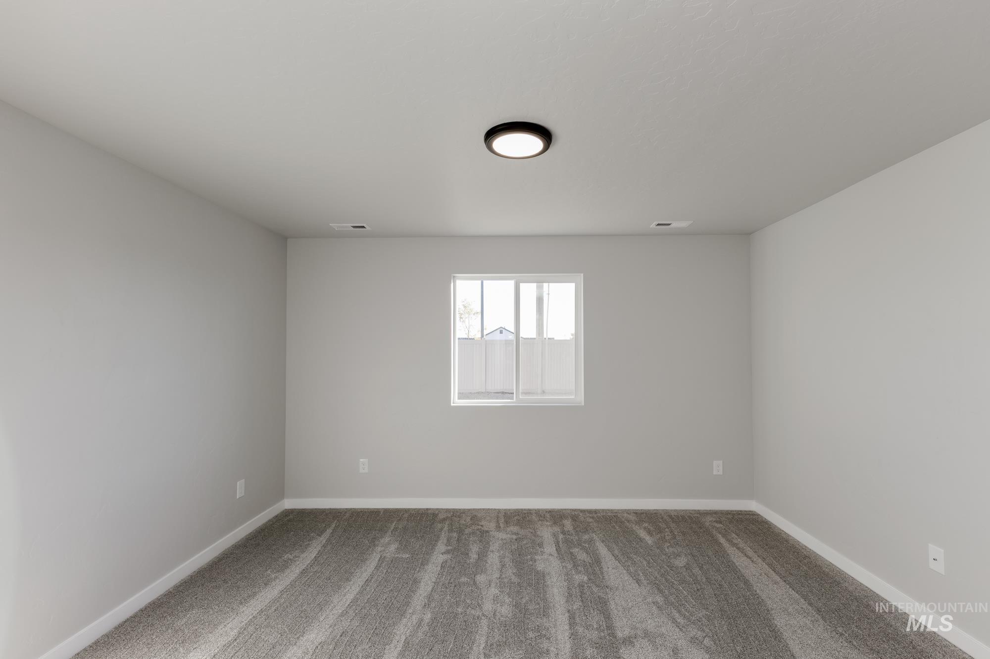 Spare room featuring carpet and baseboards