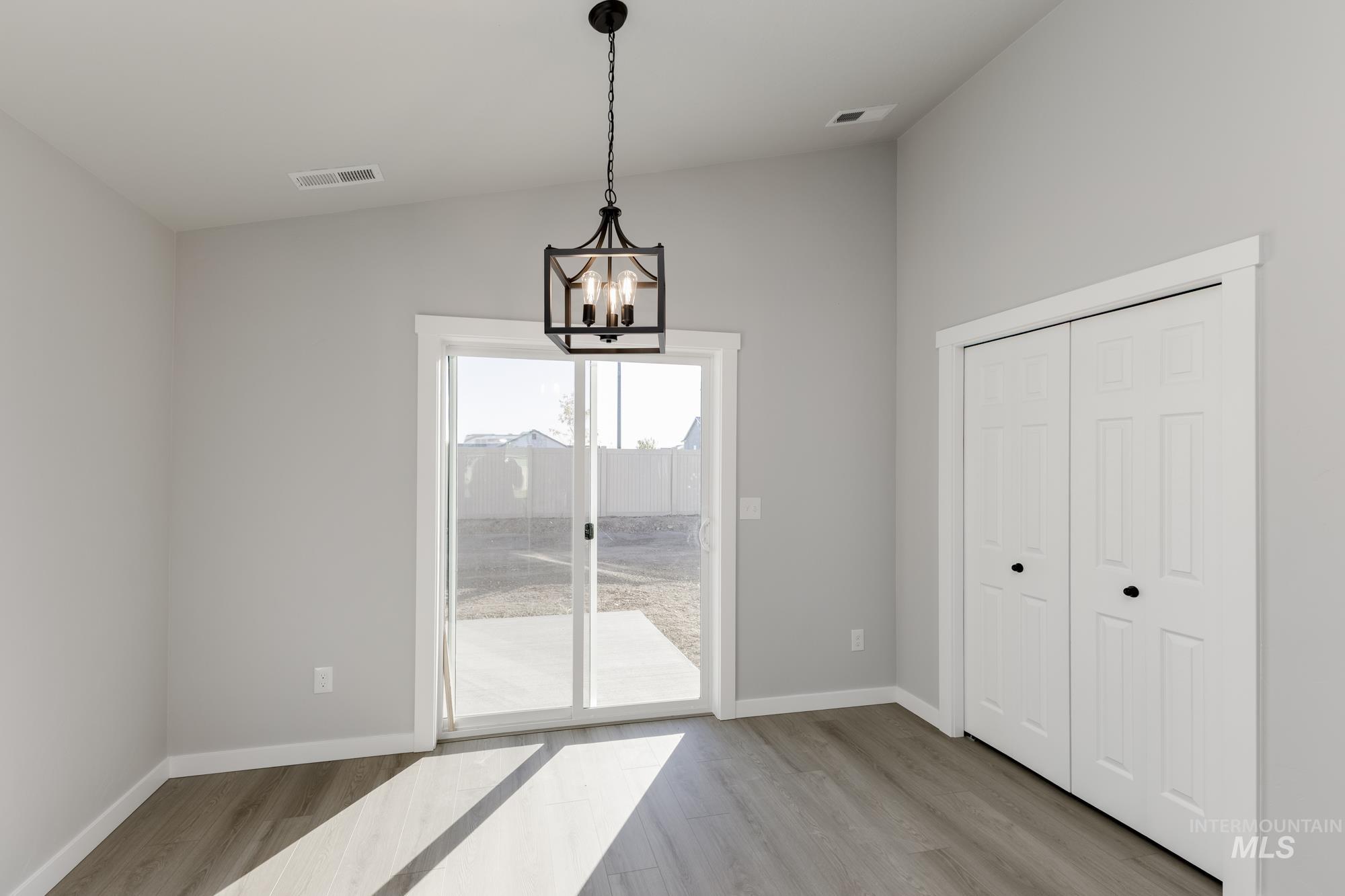 Unfurnished dining area with lofted ceiling, light wood-type flooring, and a chandelier