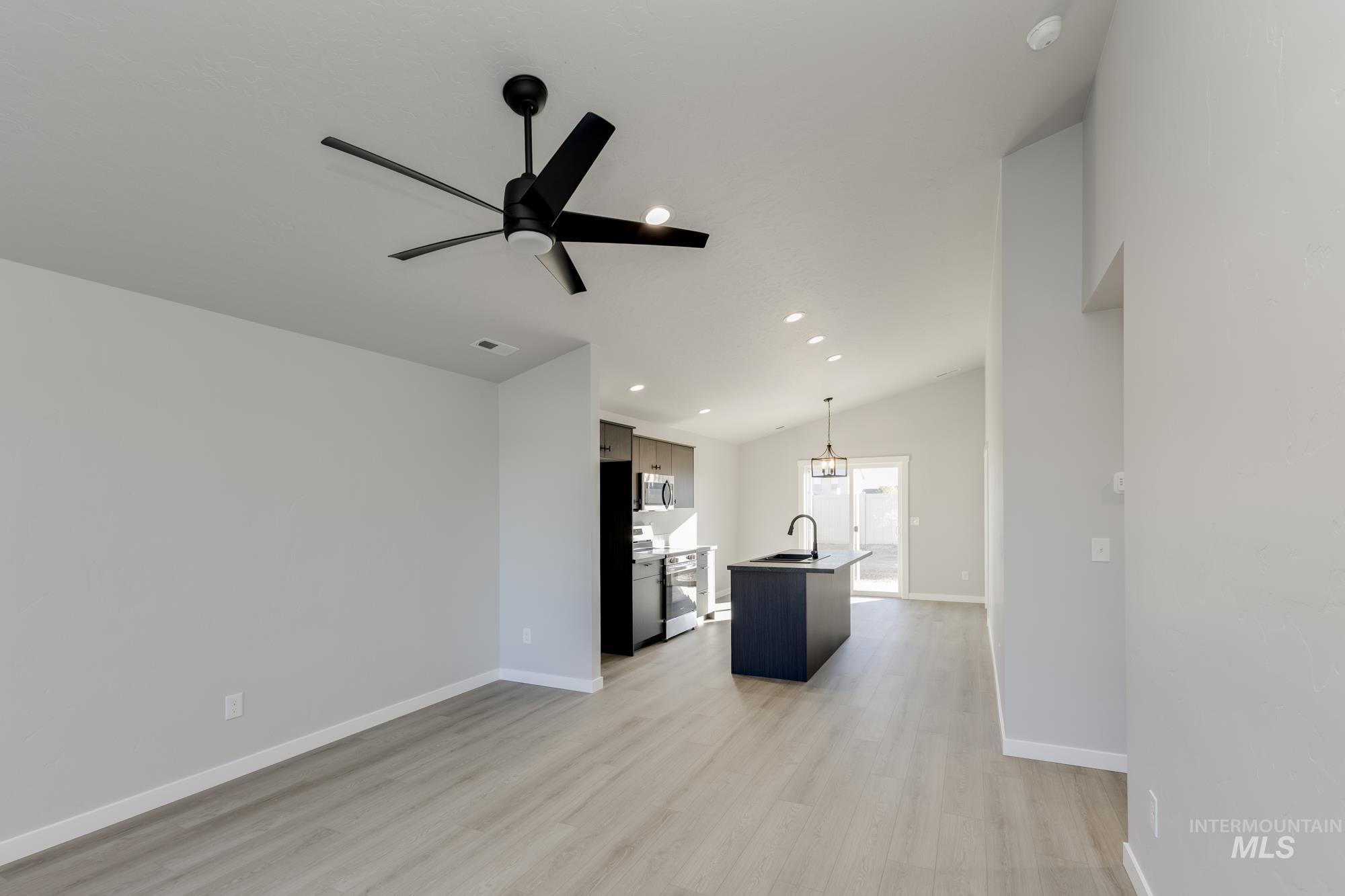 Unfurnished living room with light wood-style flooring, ceiling fan, recessed lighting, and lofted ceiling