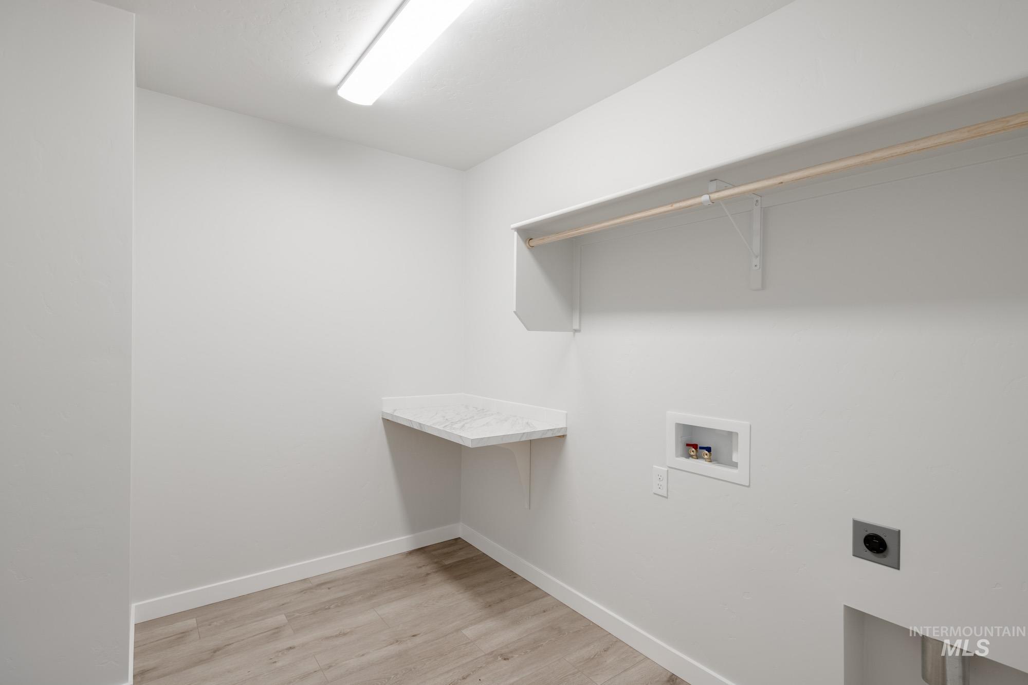 Laundry room with washer hookup, light wood-style floors, and electric dryer hookup