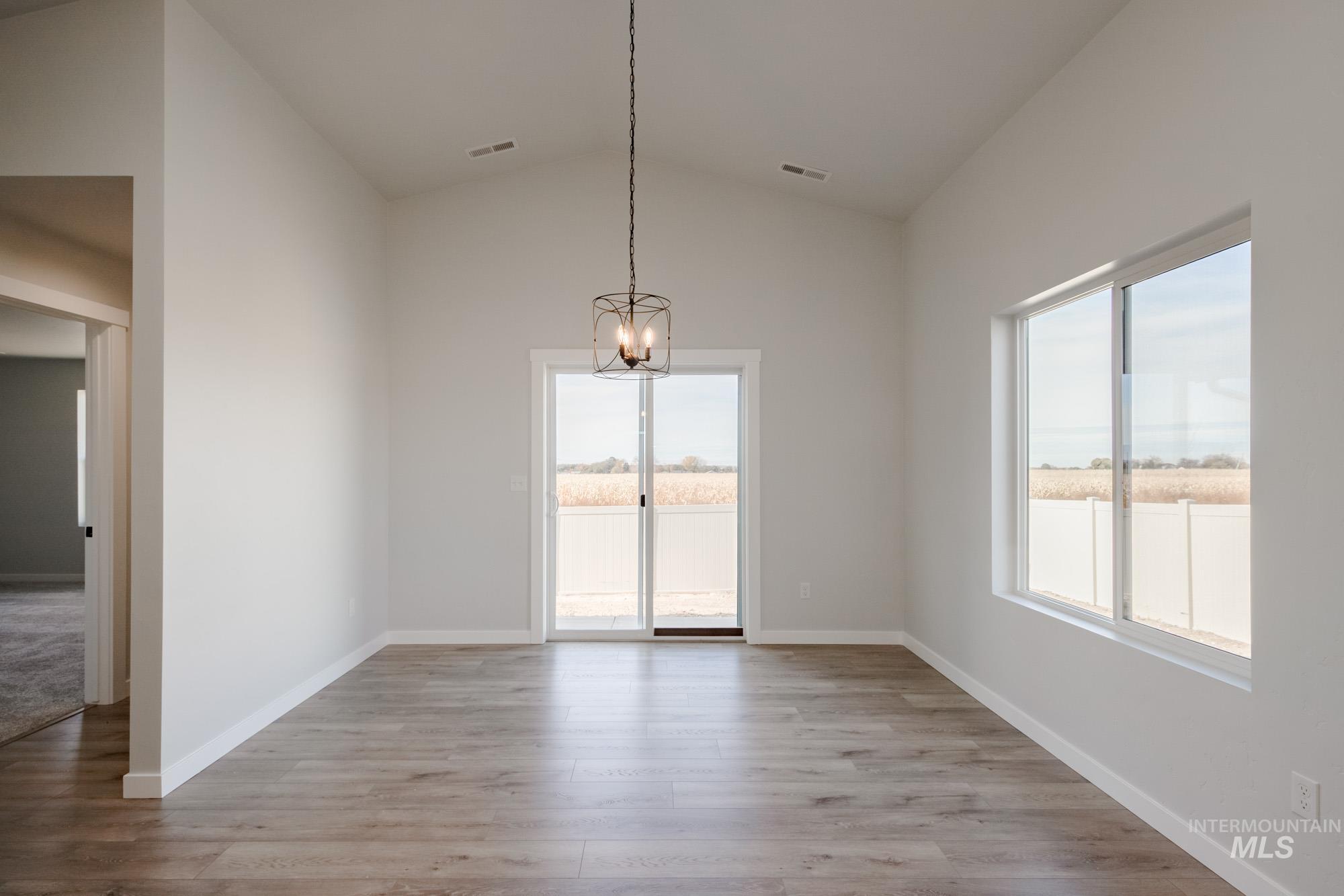 Unfurnished dining area featuring lofted ceiling, light wood-type flooring, and a chandelier