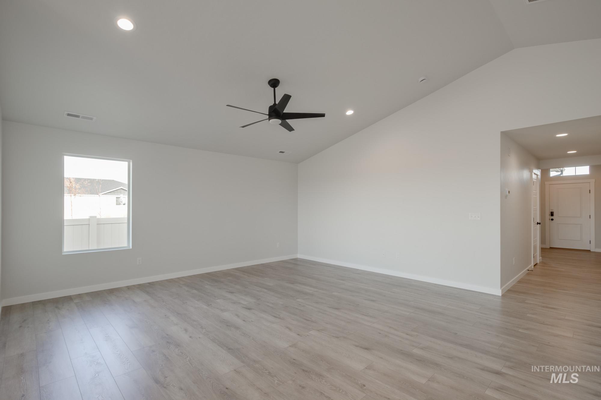 Empty room featuring vaulted ceiling, plenty of natural light, light wood-style flooring, recessed lighting, and ceiling fan