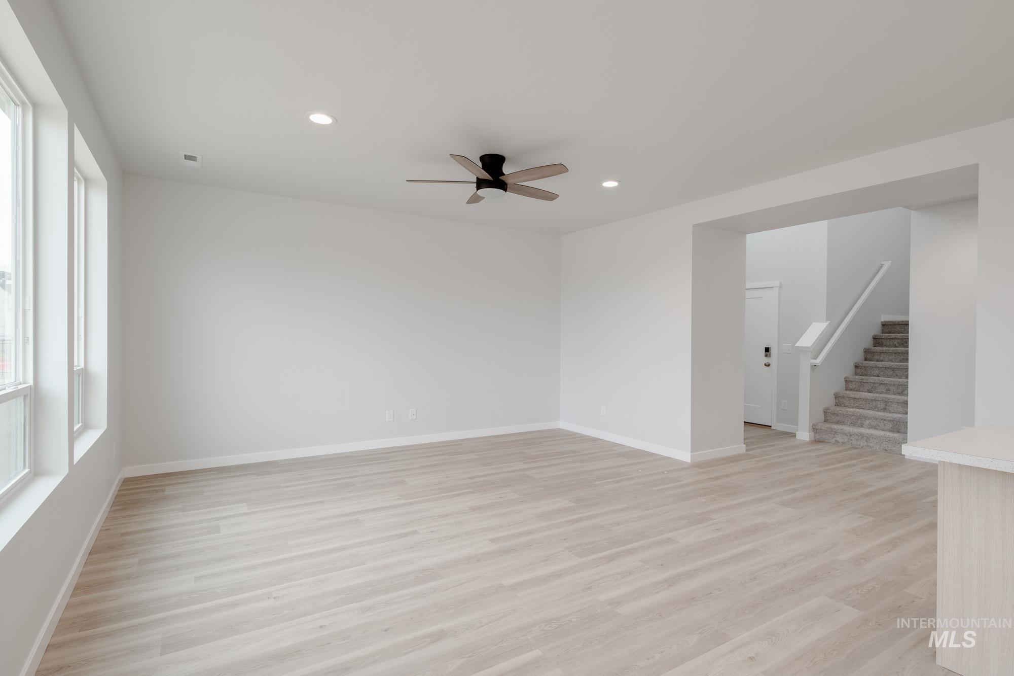 Empty room featuring light wood-type flooring, stairway, a ceiling fan, and recessed lighting