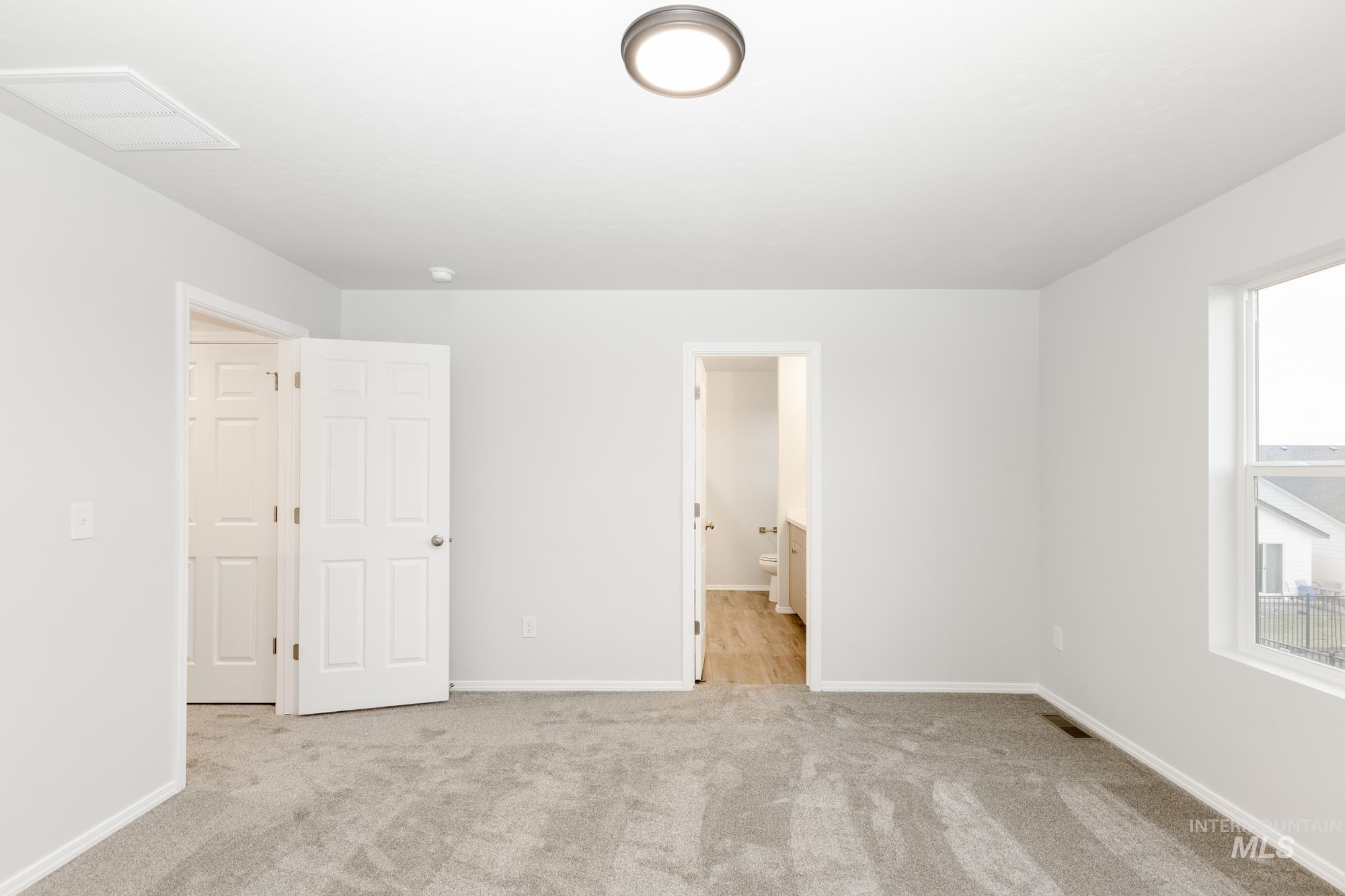 Unfurnished bedroom featuring light carpet and connected bathroom