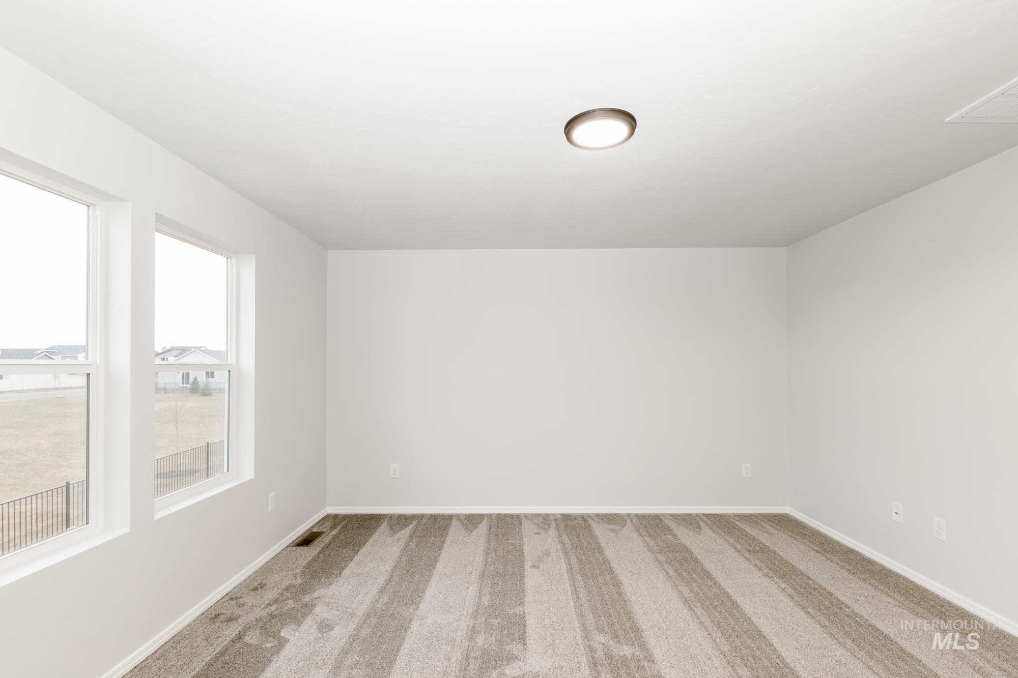 Carpeted spare room featuring baseboards
