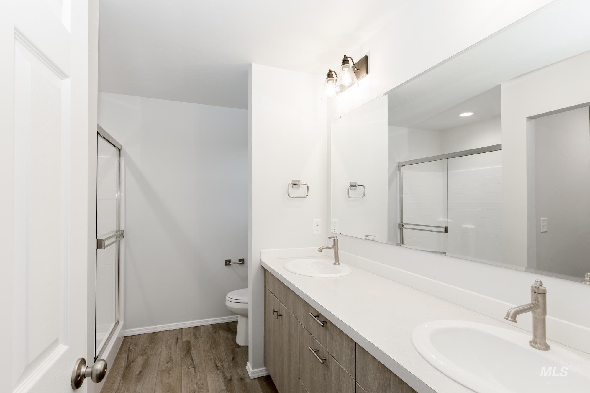 Full bath with light wood-style flooring, a stall shower, and double vanity