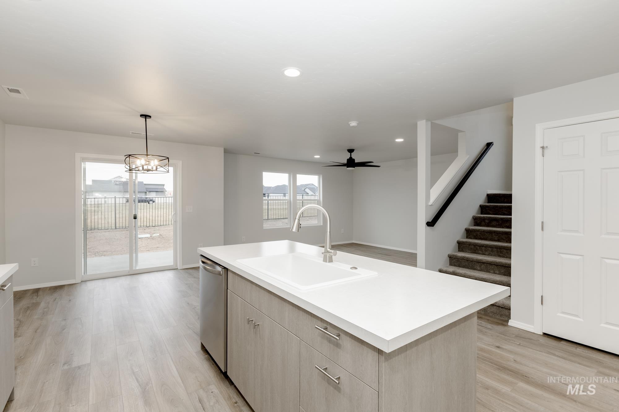 Kitchen featuring light countertops, light wood-type flooring, light brown cabinetry, hanging light fixtures, and a ceiling fan