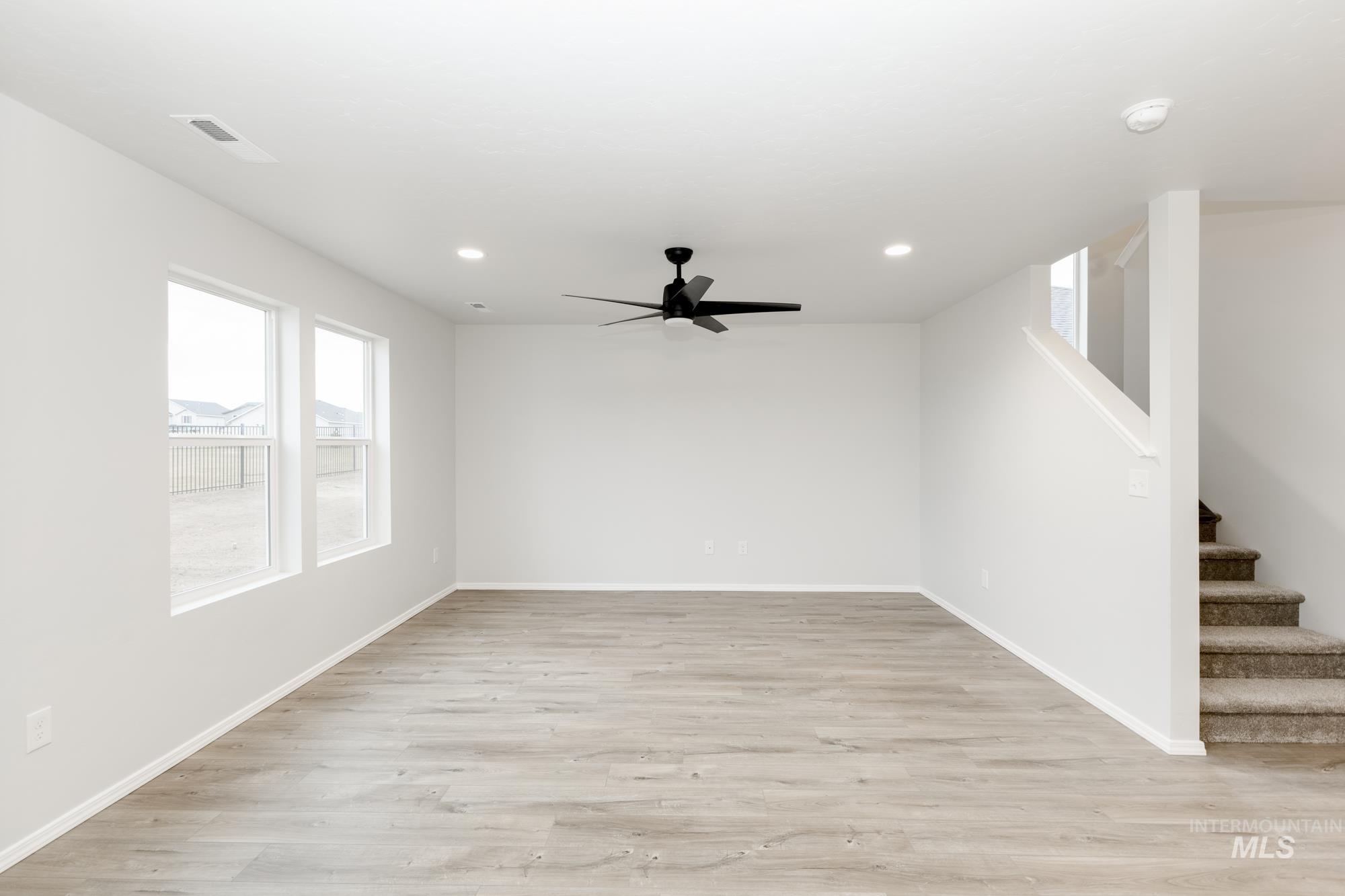 Empty room featuring light wood finished floors, stairway, recessed lighting, and ceiling fan