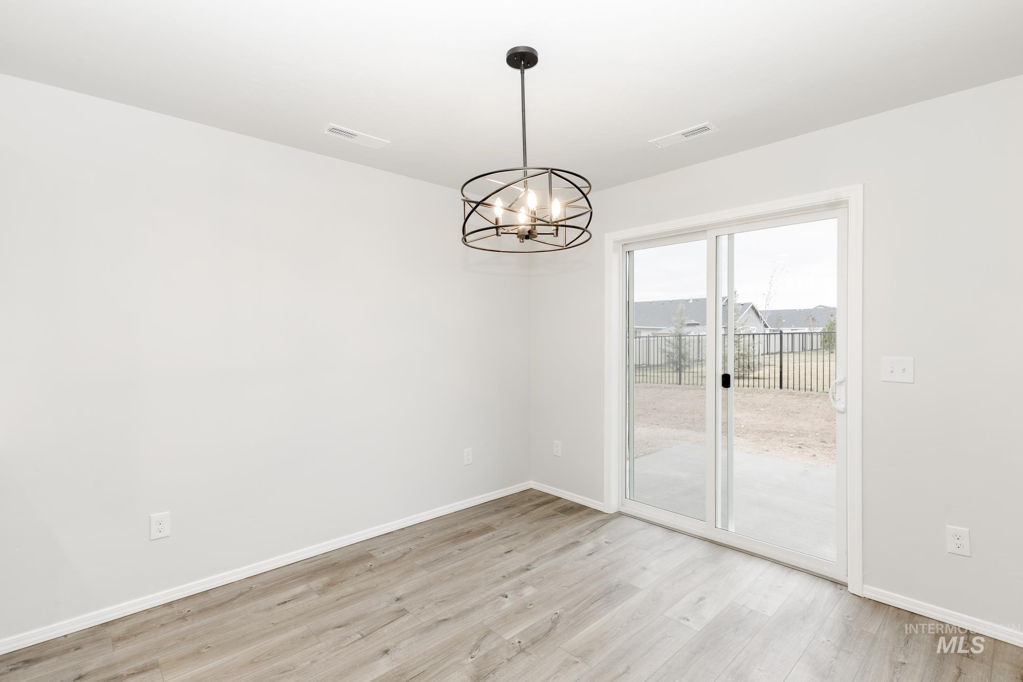 Spare room featuring a chandelier and light wood-type flooring
