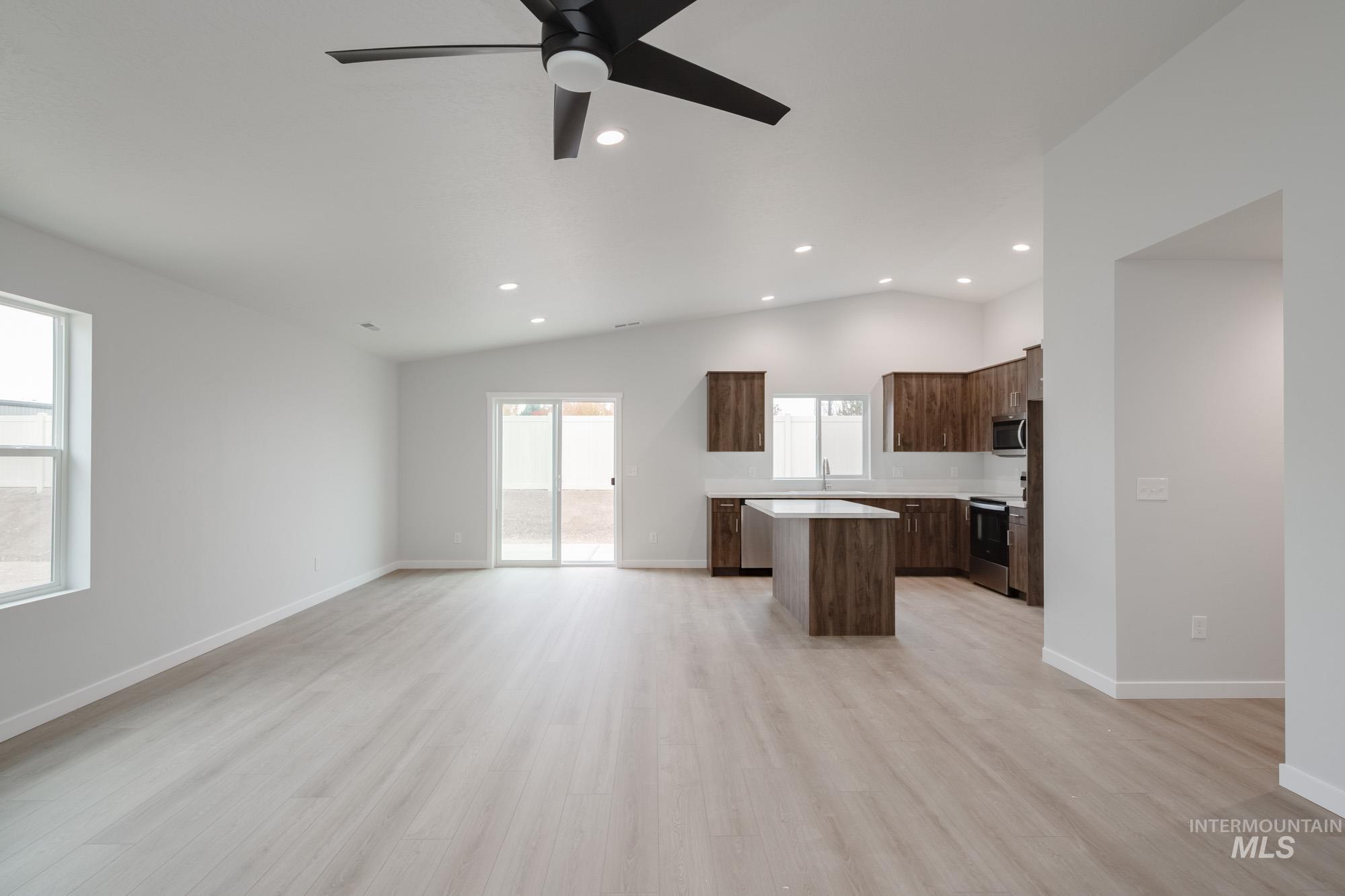 Kitchen with a kitchen island, open floor plan, light countertops, light wood-type flooring, and dark brown cabinetry