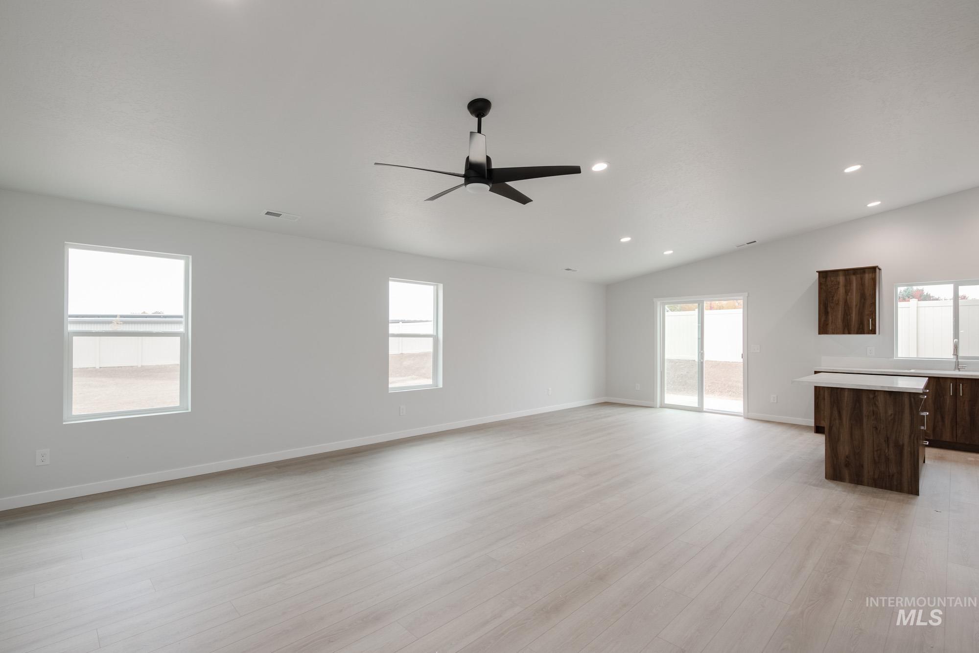 Unfurnished living room with light wood-style flooring, recessed lighting, vaulted ceiling, and ceiling fan