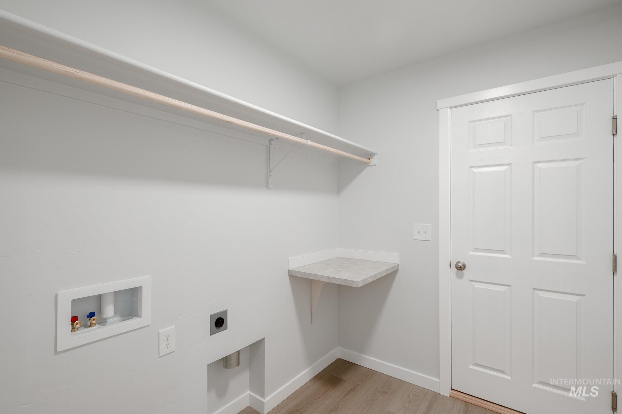 Laundry area featuring light wood-style floors, hookup for a washing machine, and hookup for an electric dryer