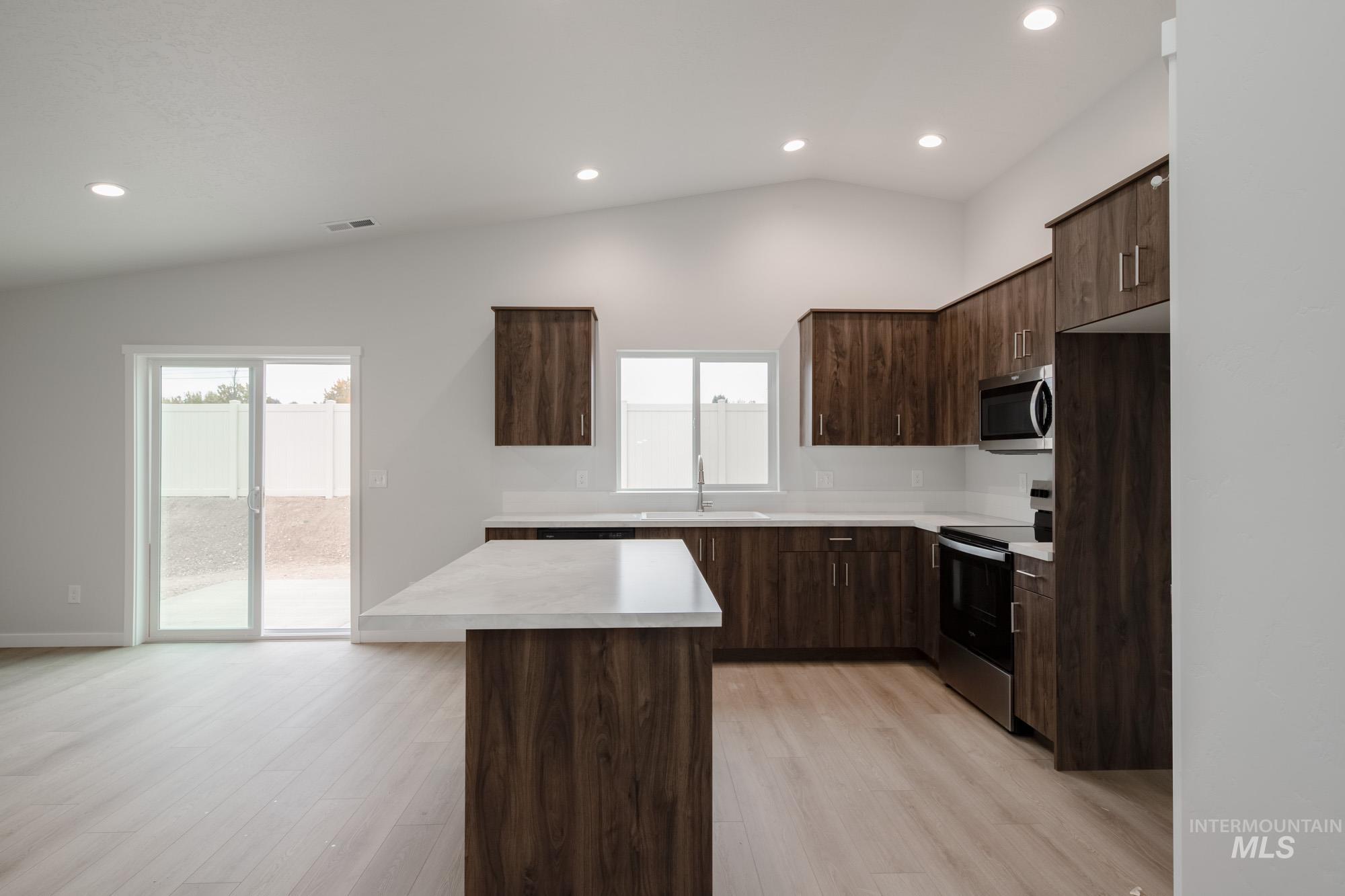 Kitchen with dark brown cabinetry, modern cabinets, light countertops, stainless steel appliances, and recessed lighting