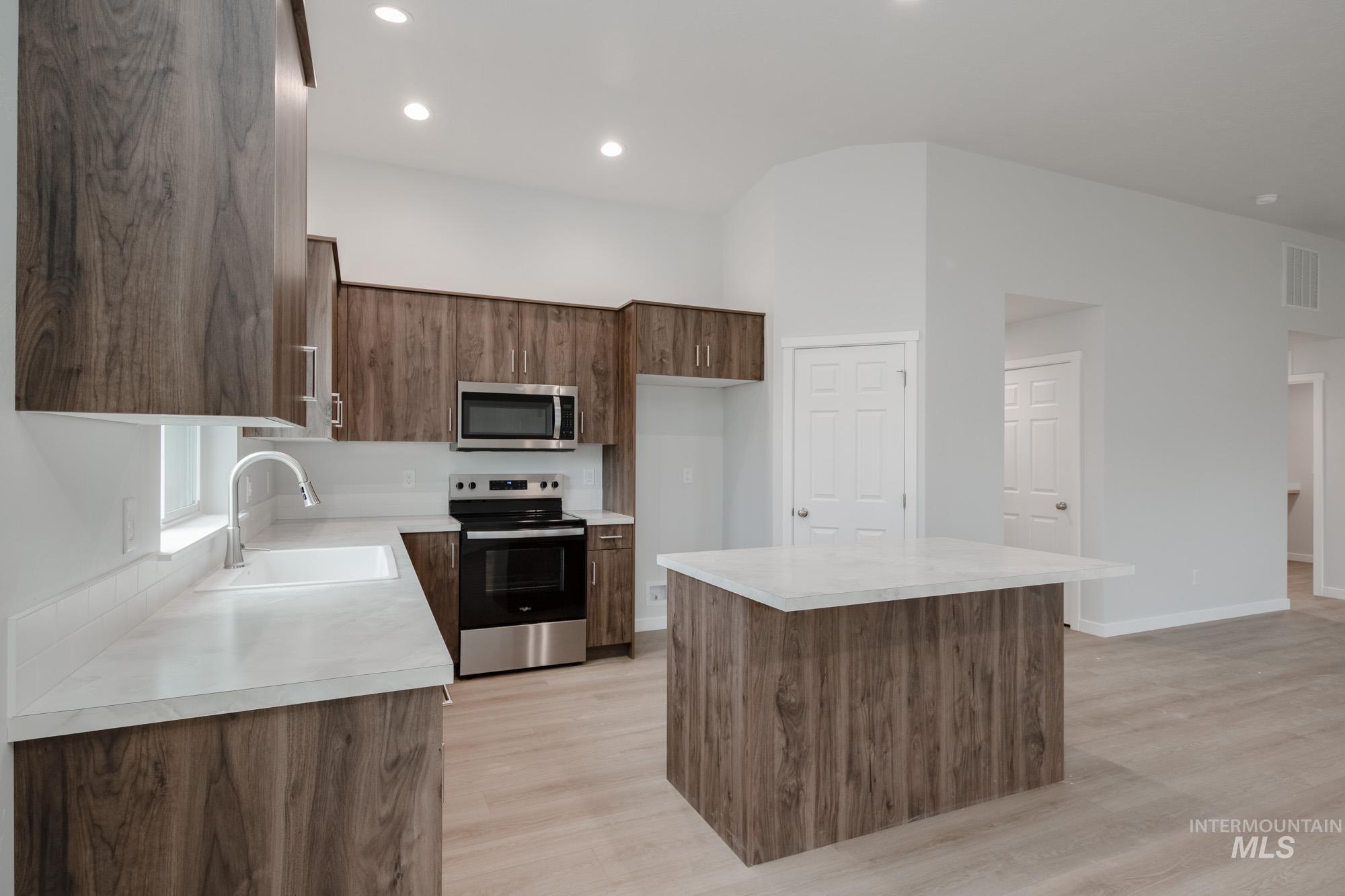 Kitchen with a kitchen island, appliances with stainless steel finishes, light countertops, light wood-style floors, and recessed lighting