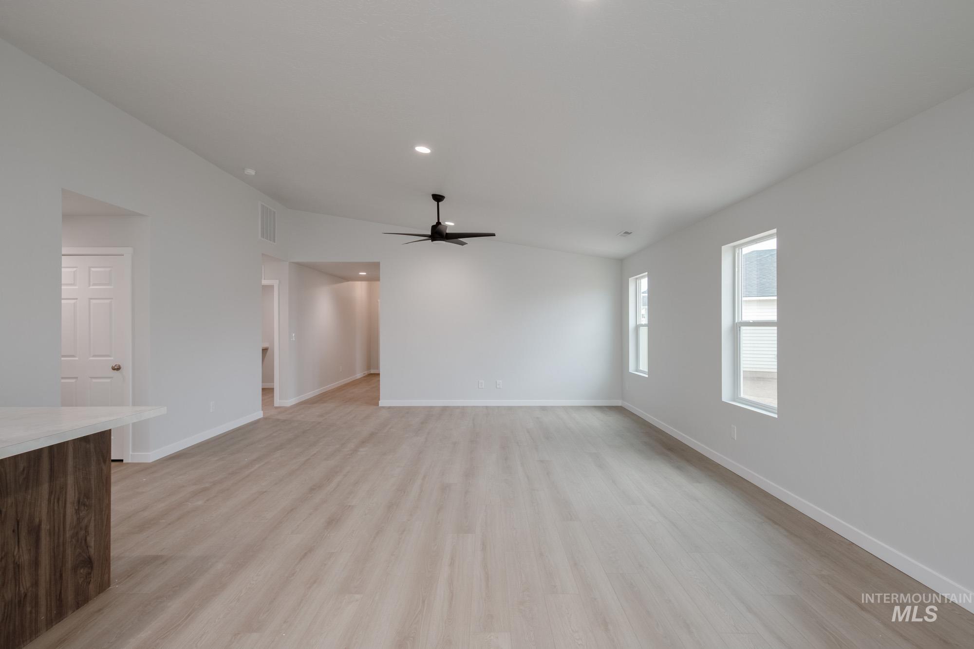 Unfurnished living room with light wood-style floors, lofted ceiling, a ceiling fan, and recessed lighting