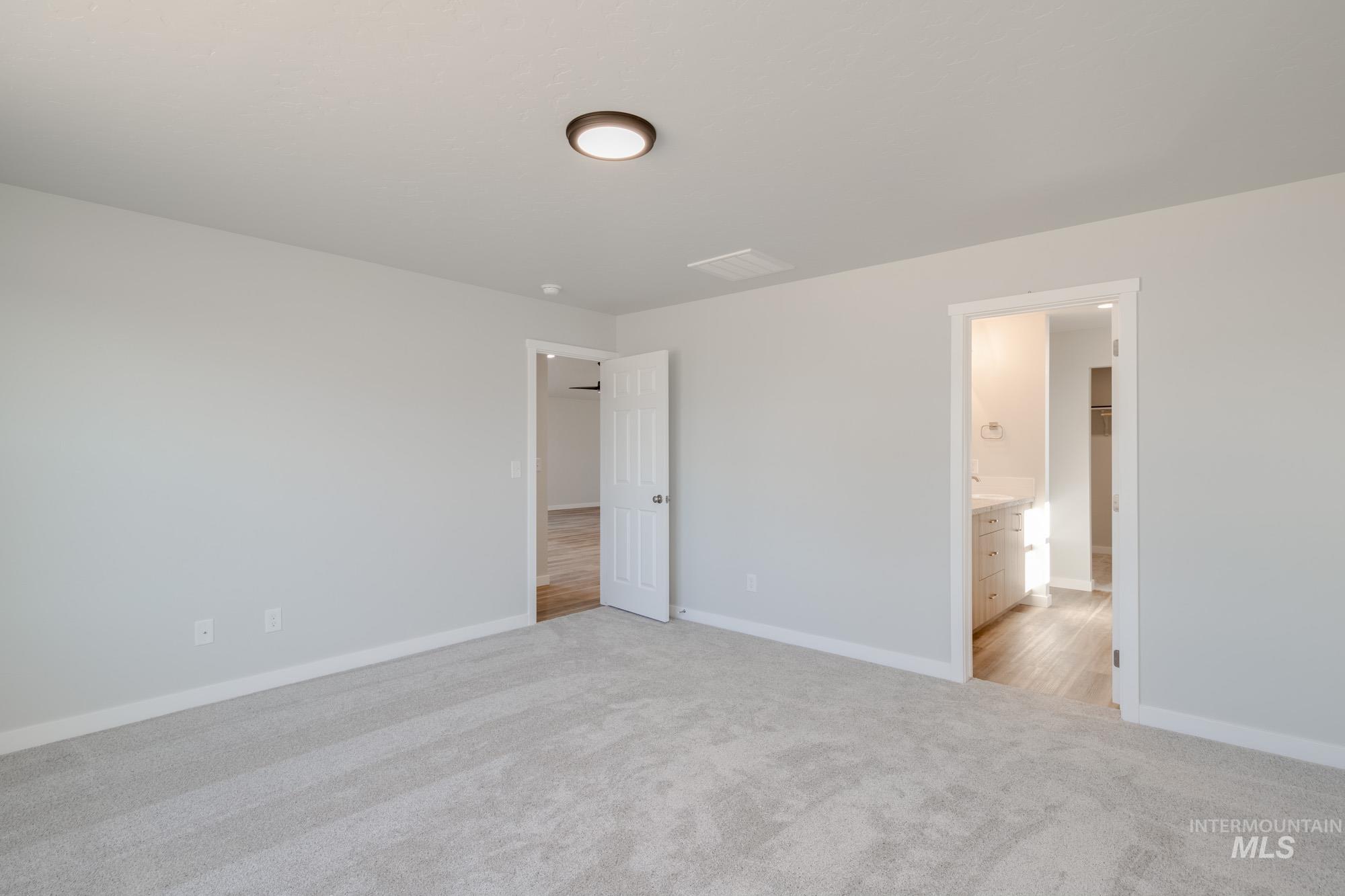 Unfurnished bedroom with light carpet and connected bathroom