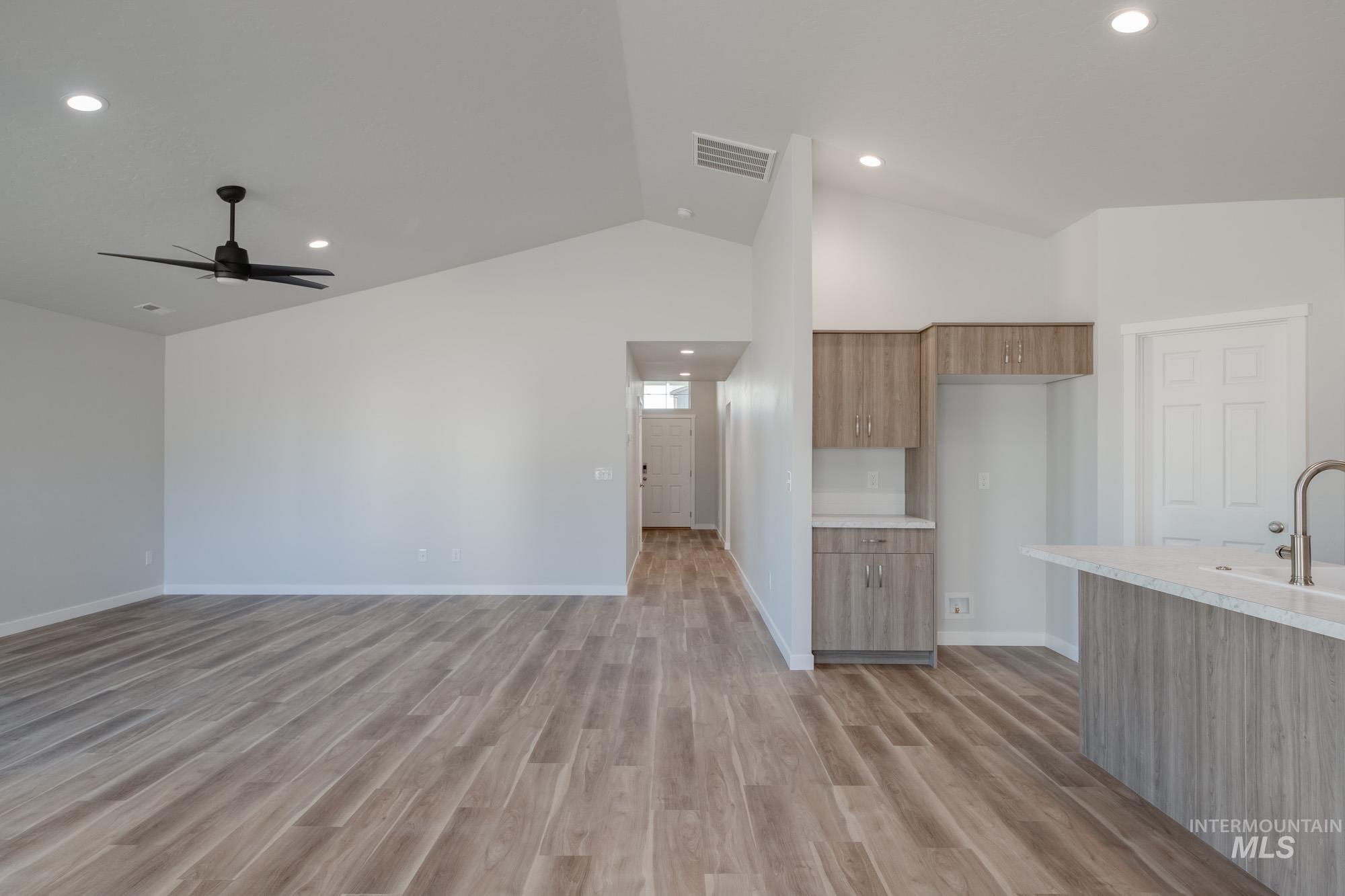 Kitchen with modern cabinets, light countertops, light wood-type flooring, ceiling fan, and open floor plan