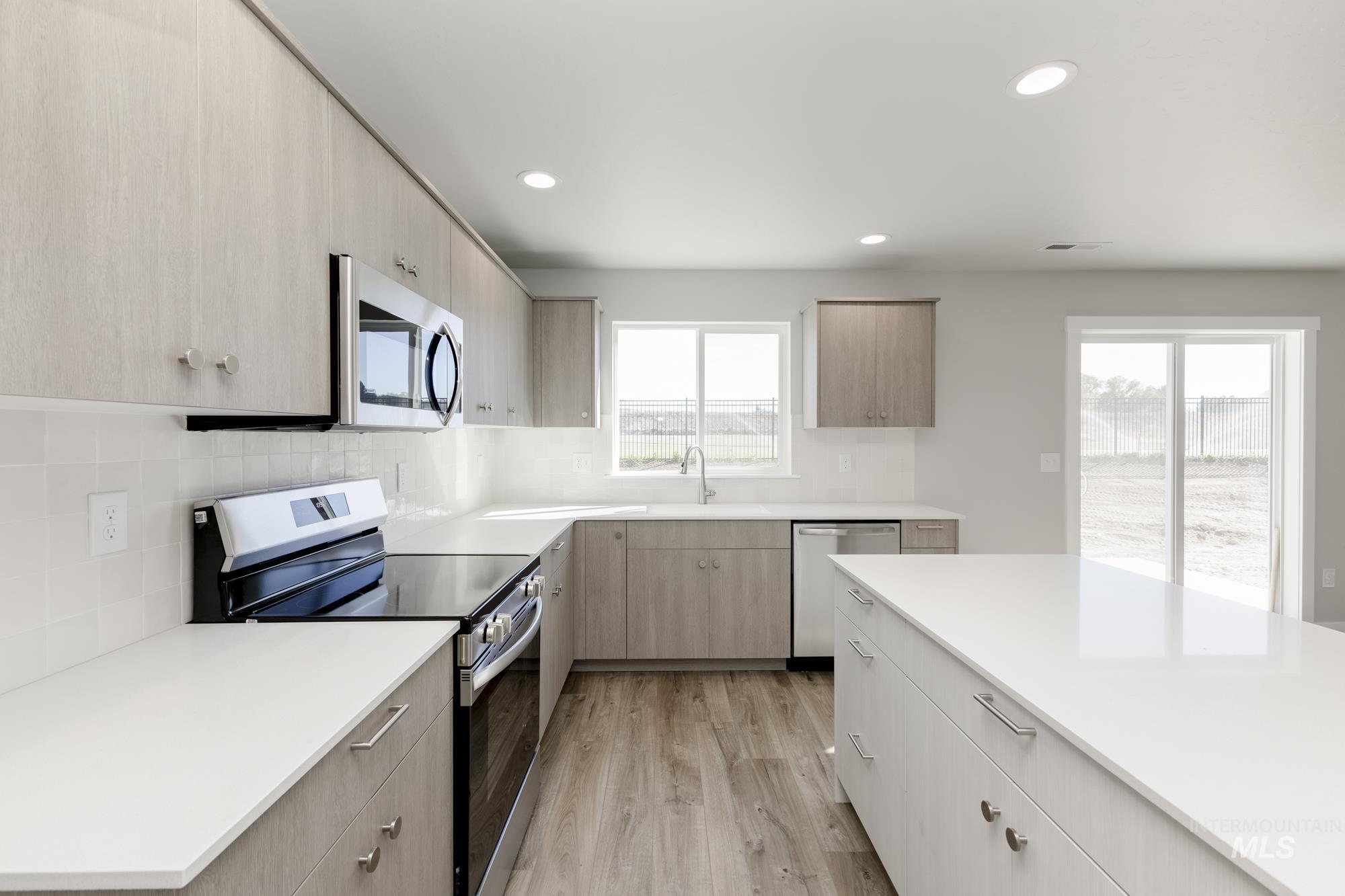 Kitchen featuring appliances with stainless steel finishes, light brown cabinets, recessed lighting, light wood-type flooring, and modern cabinets