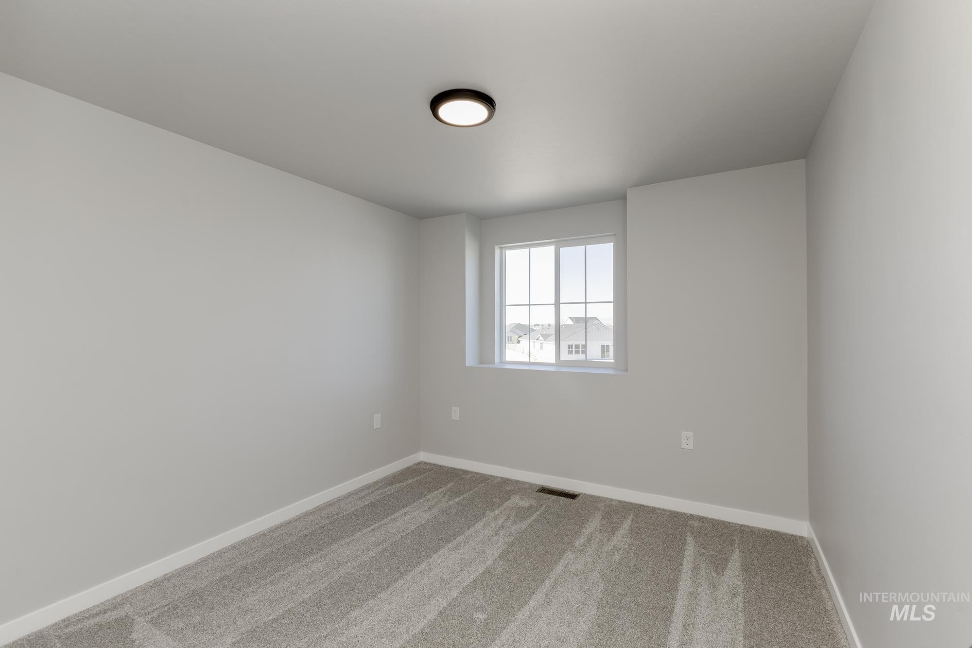 Carpeted spare room featuring baseboards