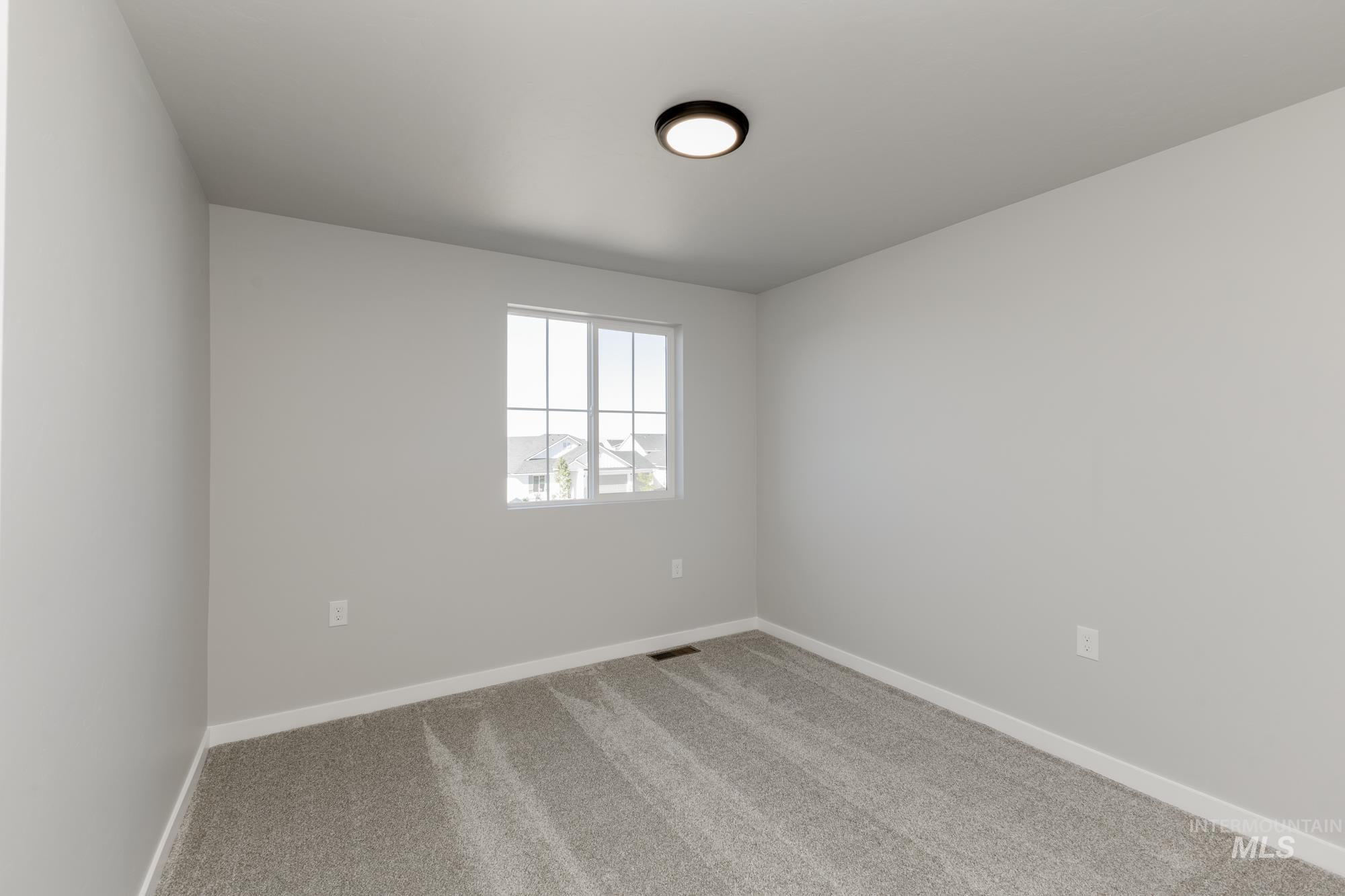 Spare room featuring carpet flooring and baseboards