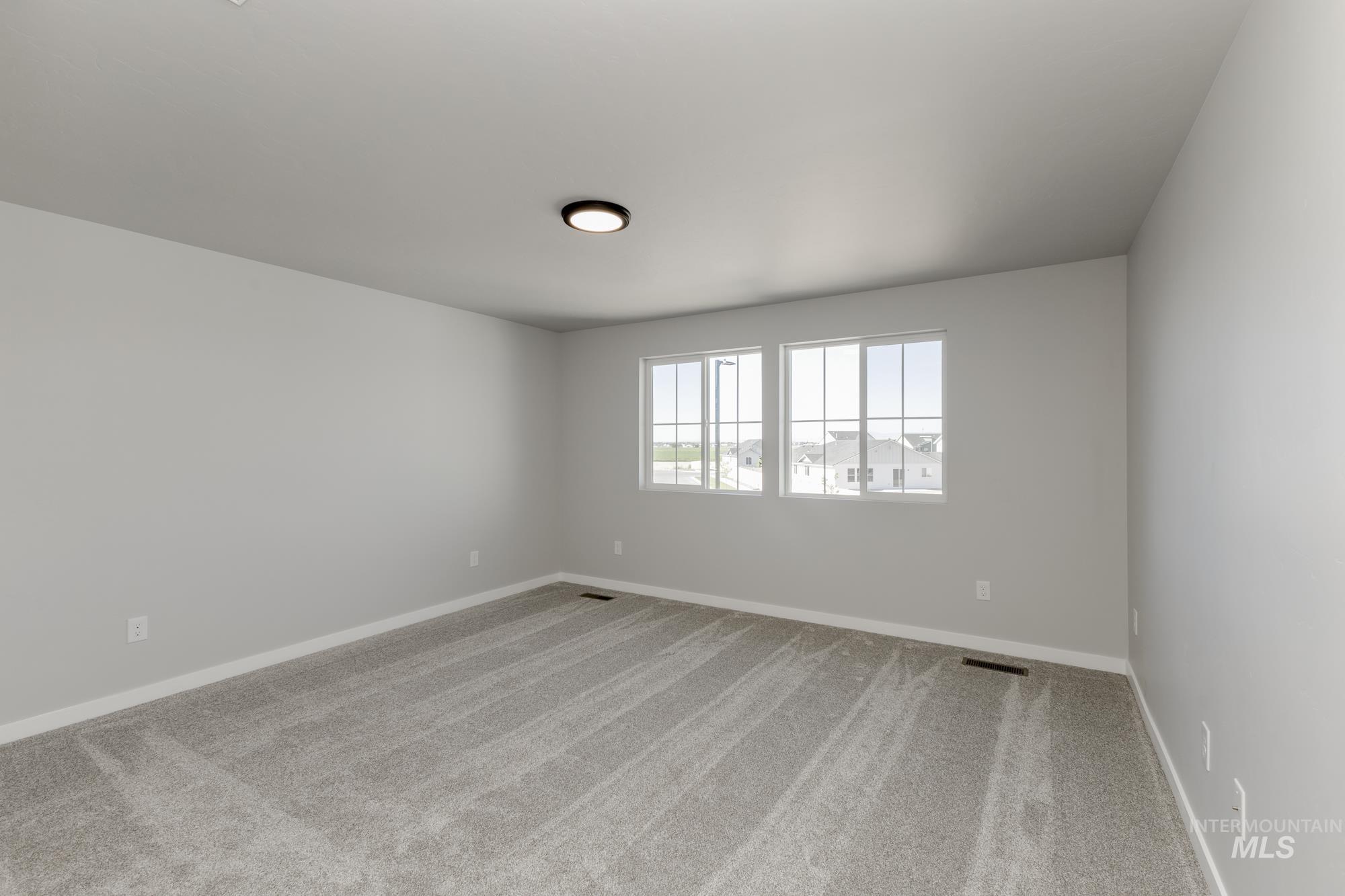 Empty room with light colored carpet and baseboards