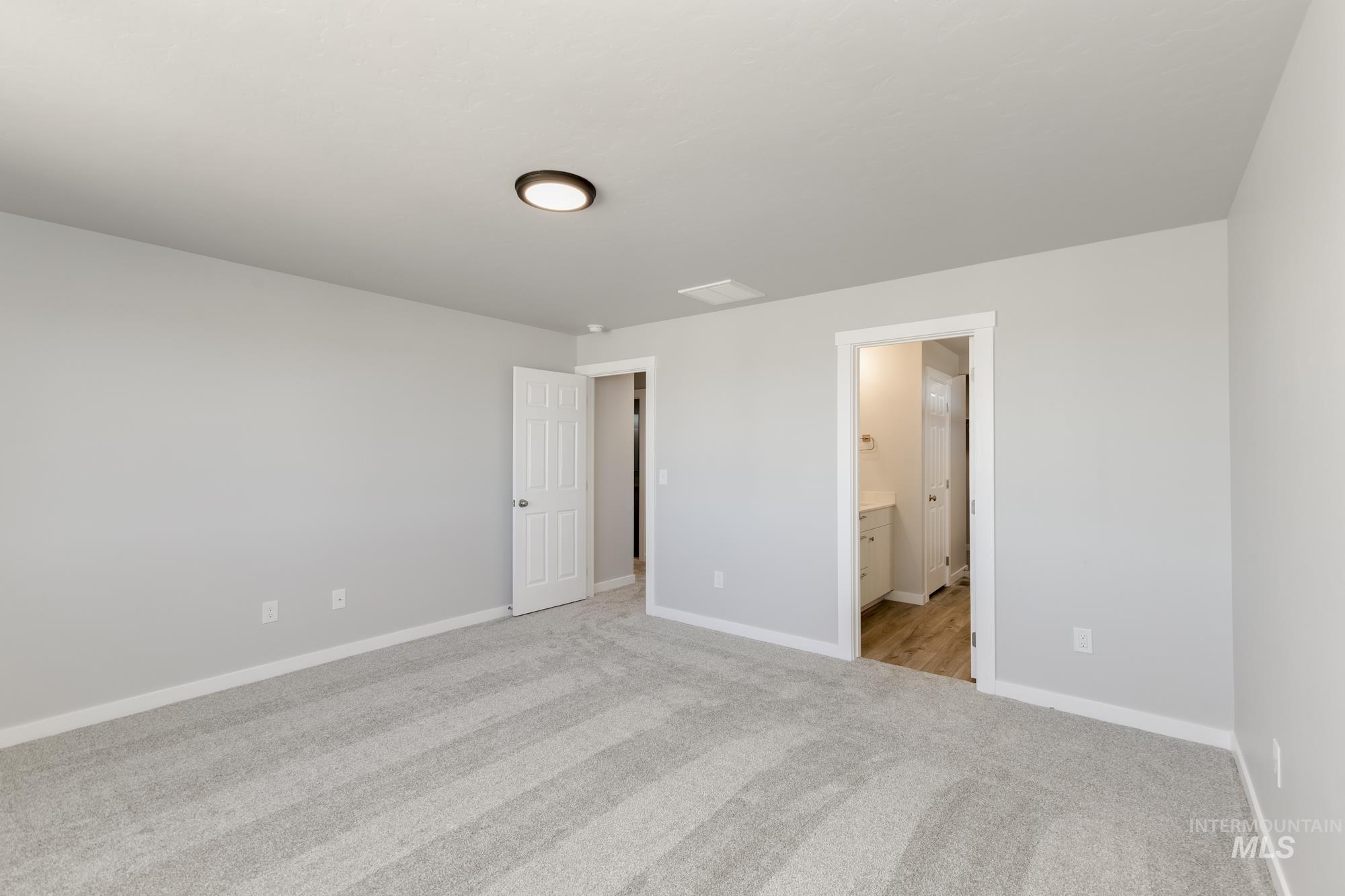 Unfurnished bedroom with light colored carpet and ensuite bath