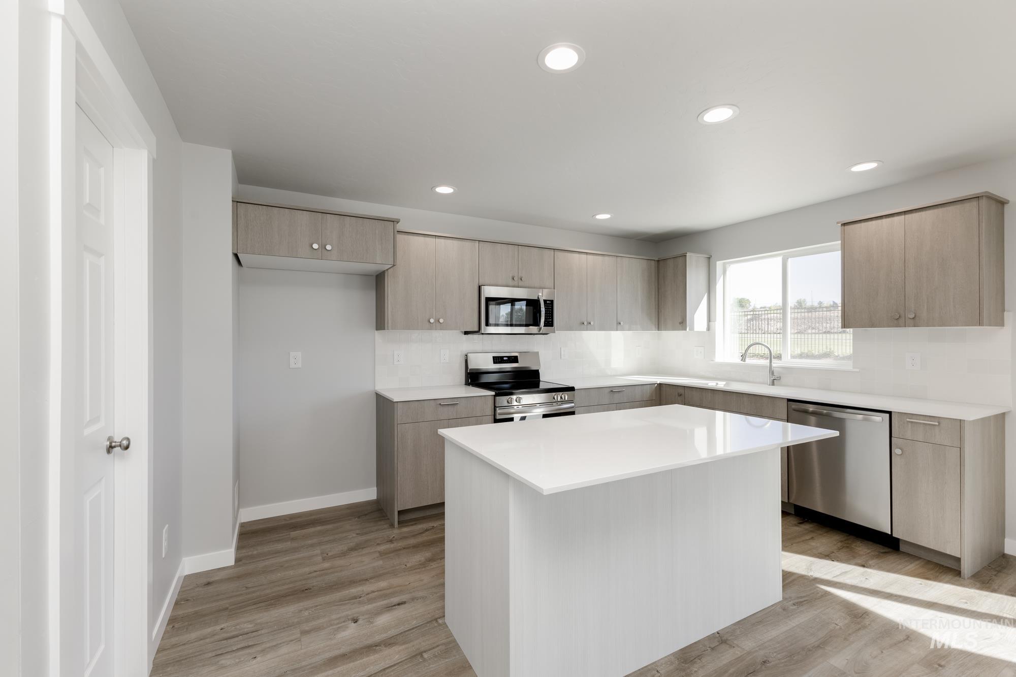 Kitchen with stainless steel appliances, light brown cabinetry, modern cabinets, a kitchen island, and light wood-style floors