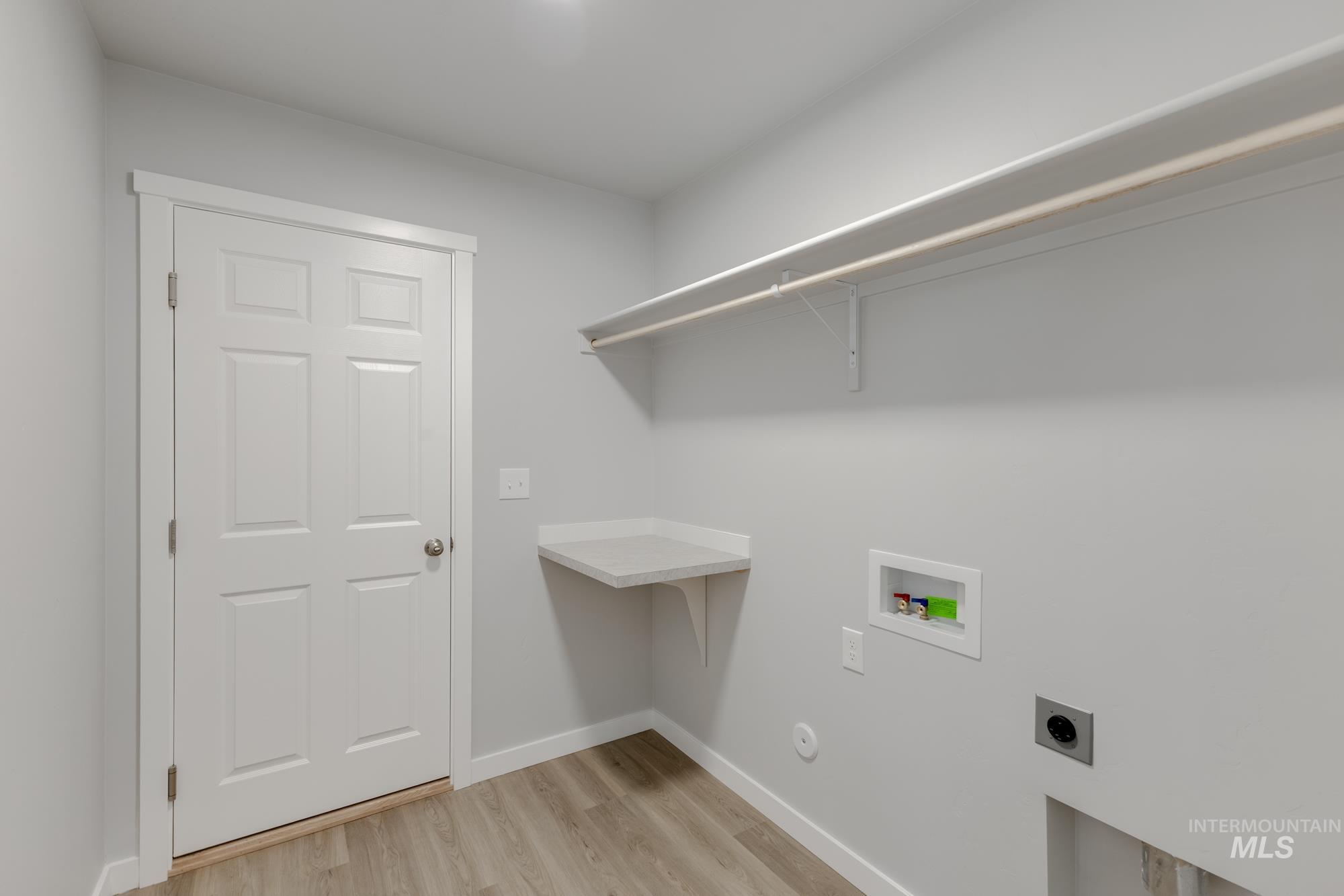 Laundry room with washer hookup, electric dryer hookup, and light wood-style floors