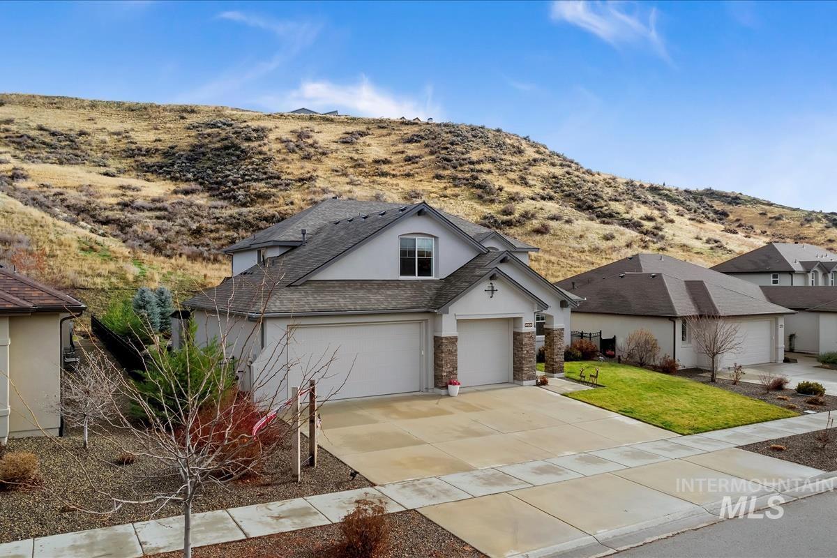 View of front of property with stucco siding, driveway, a garage, a front lawn, and stone siding