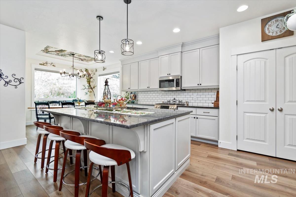 Kitchen featuring a kitchen bar, a center island, pendant lighting, light wood finished floors, and dark stone counters