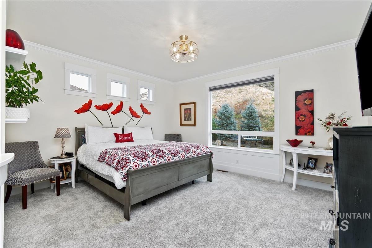 Bedroom featuring light carpet, ornamental molding, and a chandelier