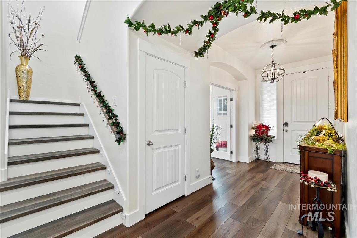 Entrance foyer with dark wood-style flooring, a chandelier, and stairs