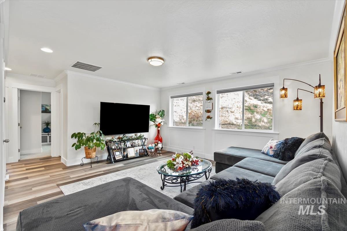 Living room featuring wood finished floors, crown molding, and recessed lighting