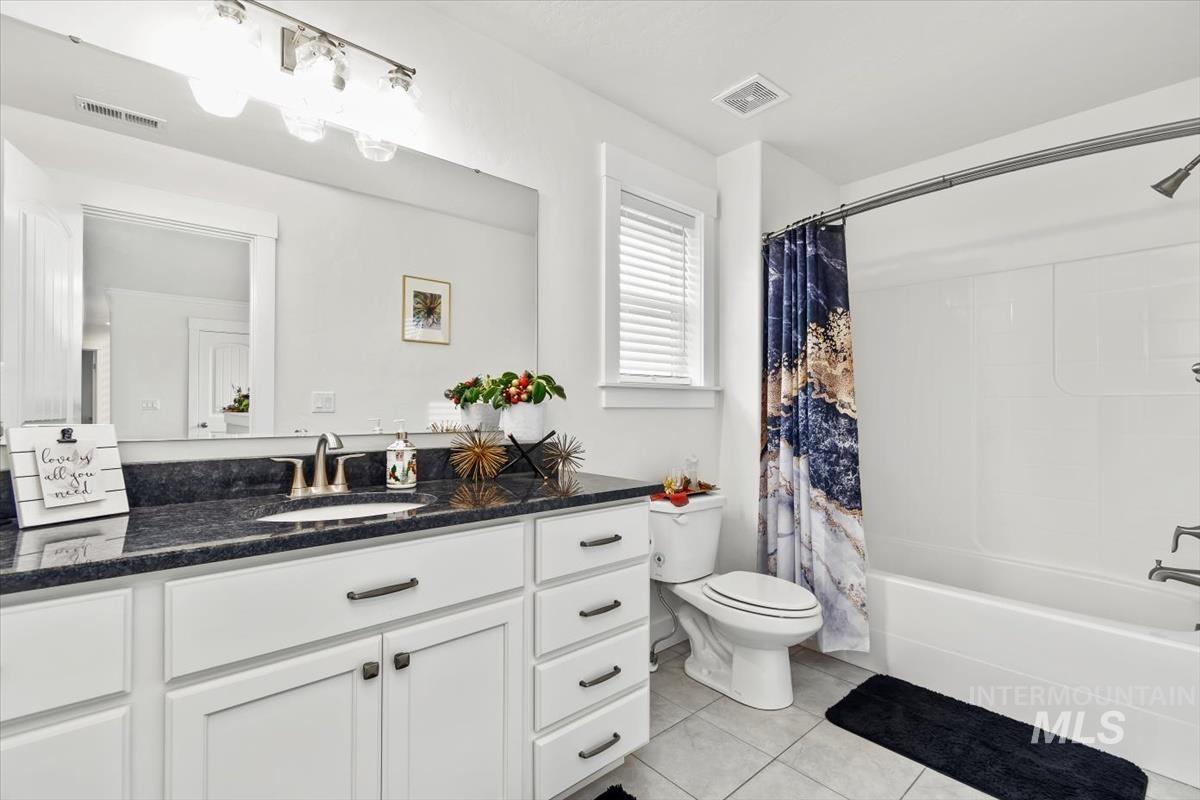 Bathroom with vanity, shower / bath combo, and light tile patterned floors