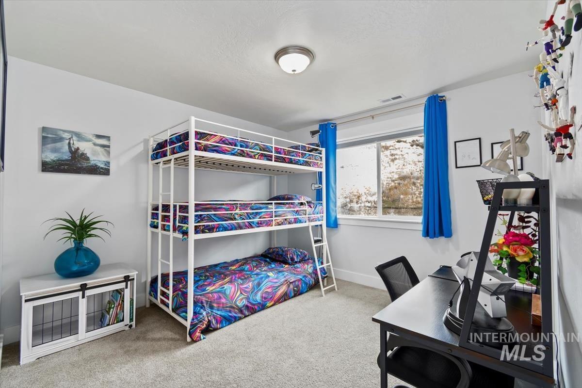 Bedroom featuring light colored carpet and a desk