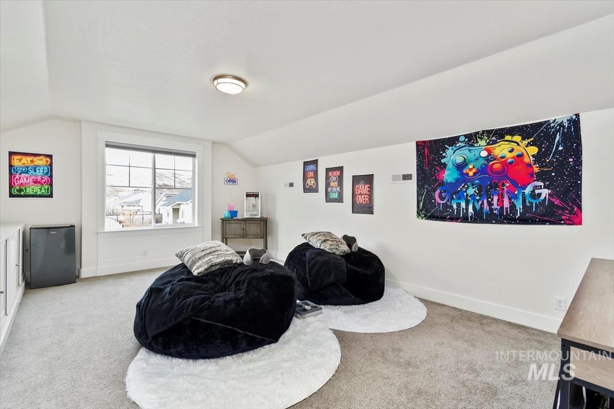 Sitting room with light colored carpet and vaulted ceiling