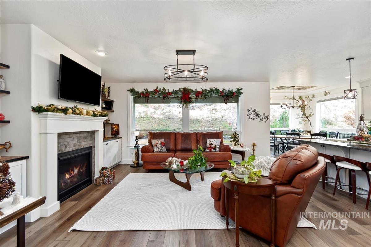 Living area with a glass covered fireplace, wood finished floors, and a chandelier