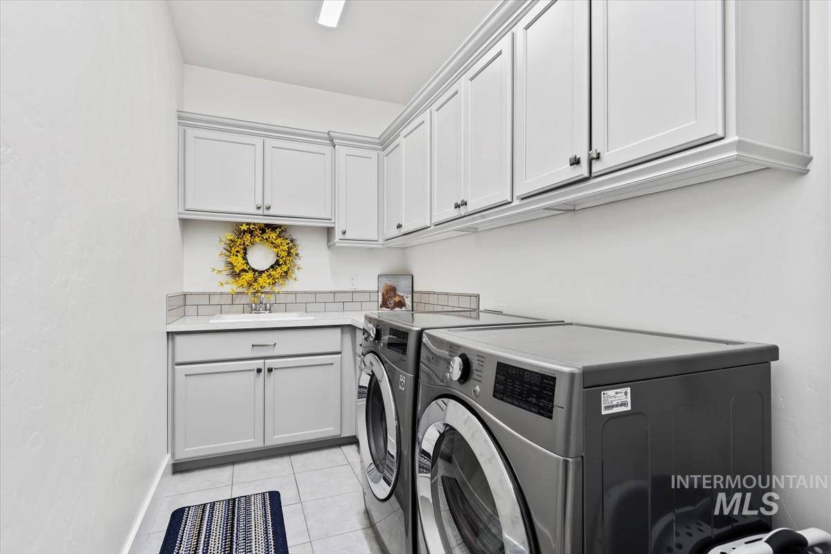 Laundry room featuring light tile patterned floors, washing machine and clothes dryer, and cabinet space