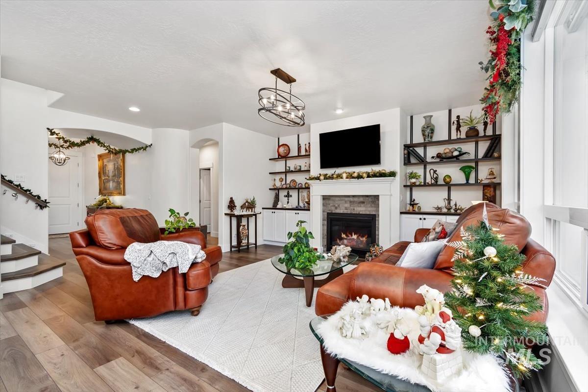 Living area featuring a fireplace, wood finished floors, recessed lighting, stairway, and a chandelier
