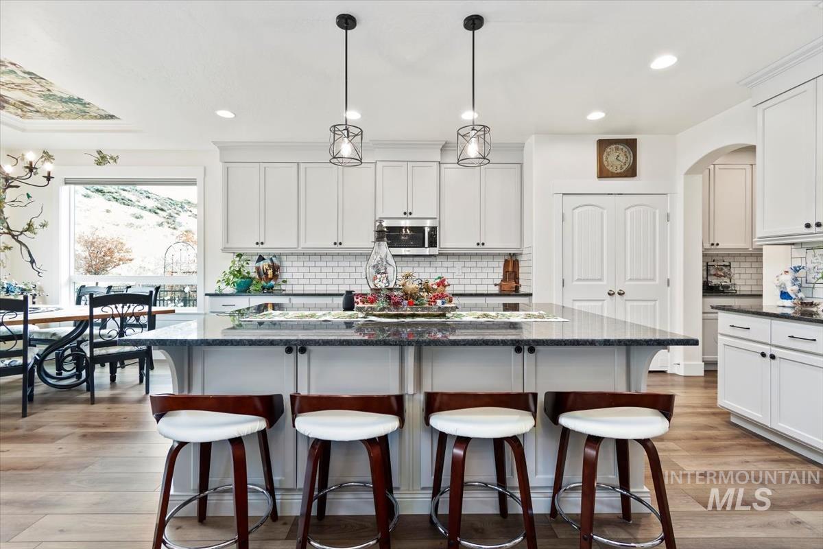 Kitchen featuring a breakfast bar area, a kitchen island, dark stone countertops, decorative light fixtures, and white cabinetry