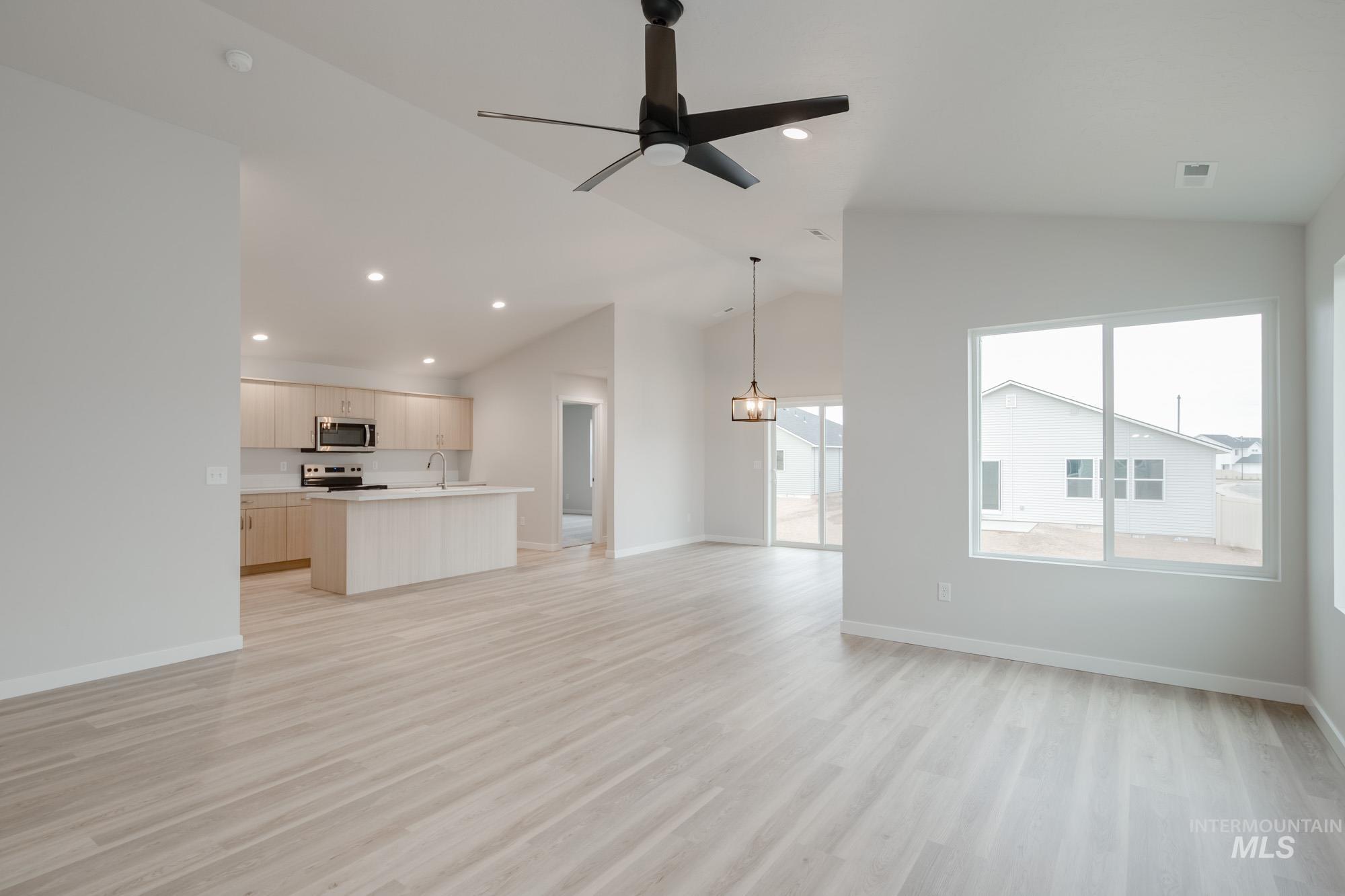 Unfurnished living room featuring a ceiling fan, light wood-style flooring, recessed lighting, a chandelier, and high vaulted ceiling