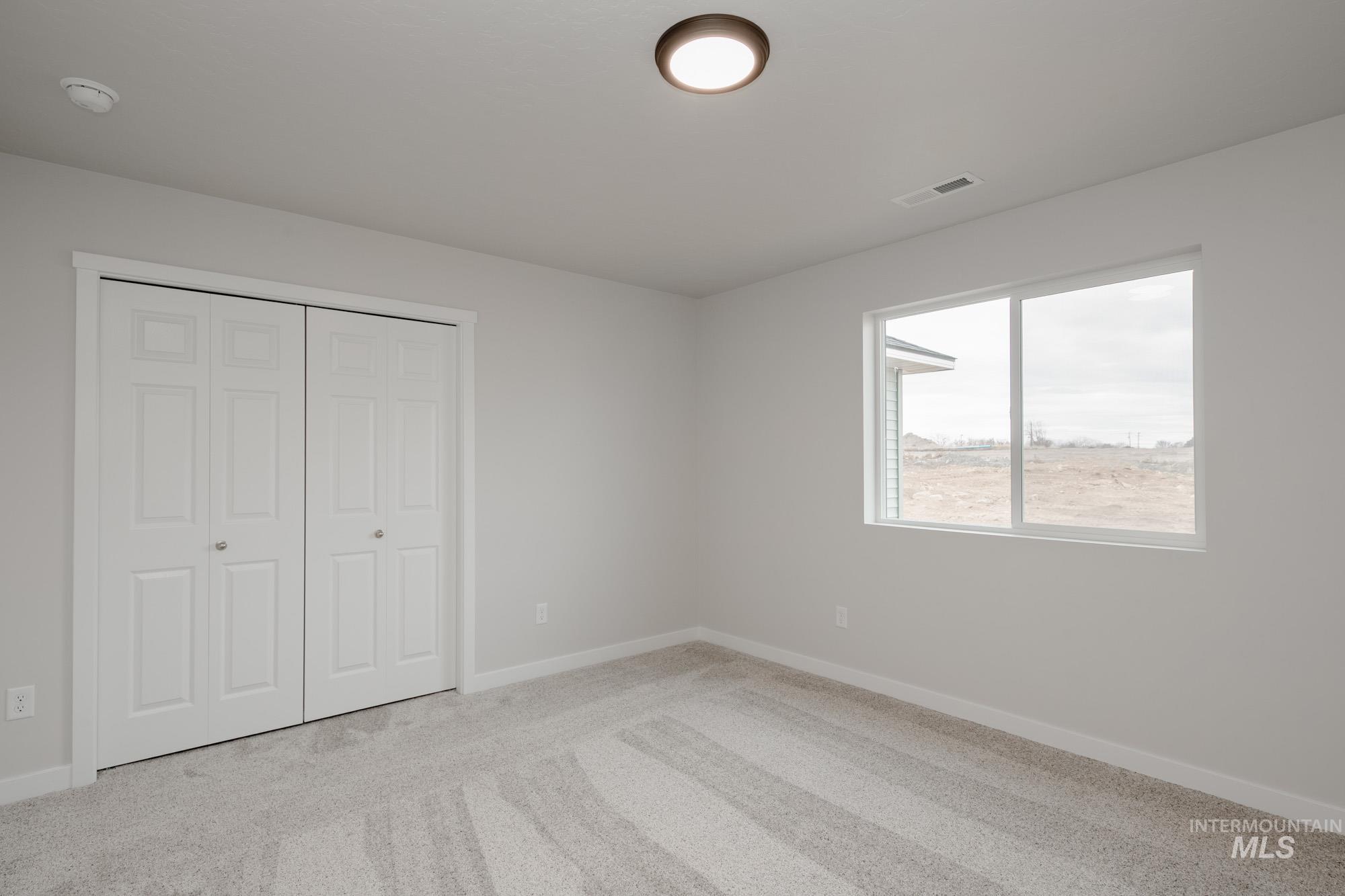 Unfurnished bedroom with light colored carpet and a closet