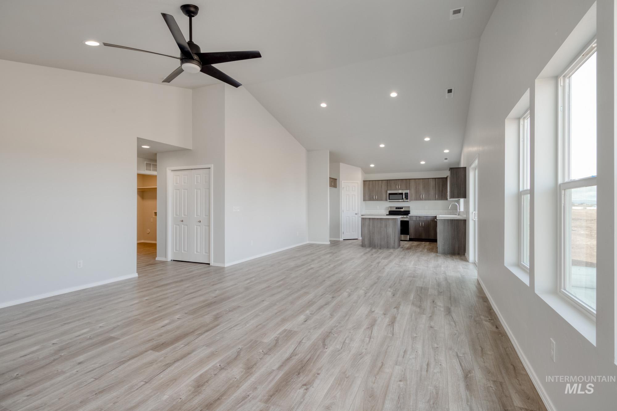 Unfurnished living room with recessed lighting, light wood finished floors, a ceiling fan, and high vaulted ceiling